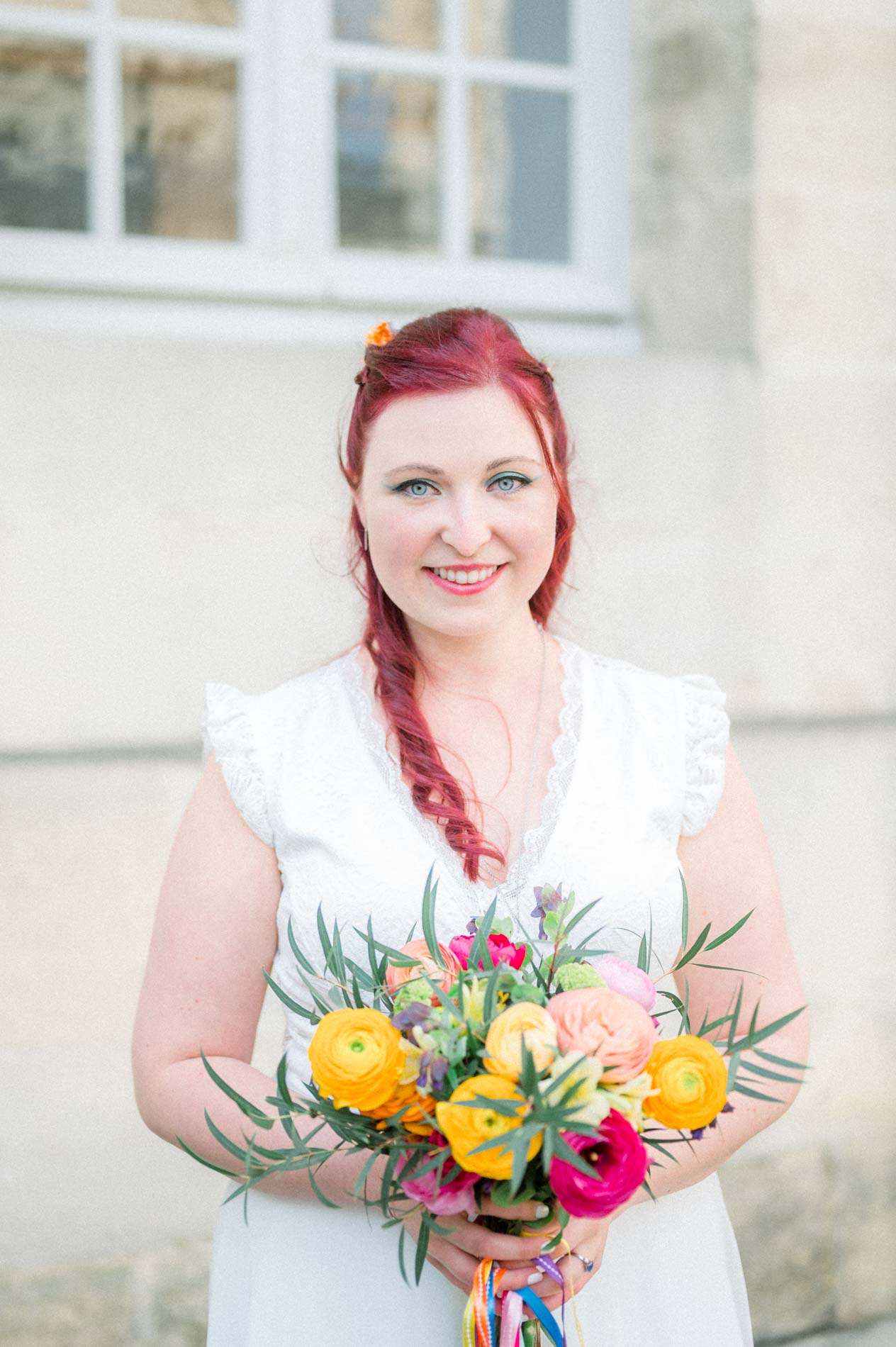 Smiling bride with her bouquet of orange and pink ranunculus