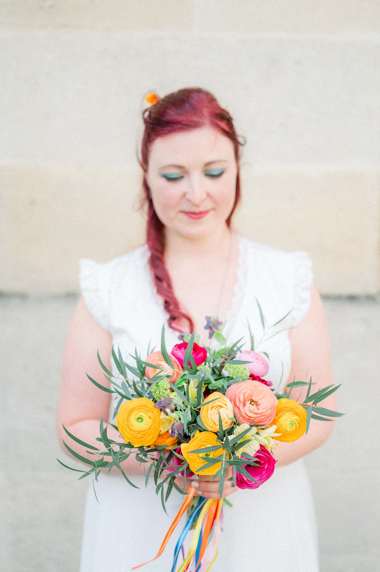 Bride looking down at her brightly coloured bouquet