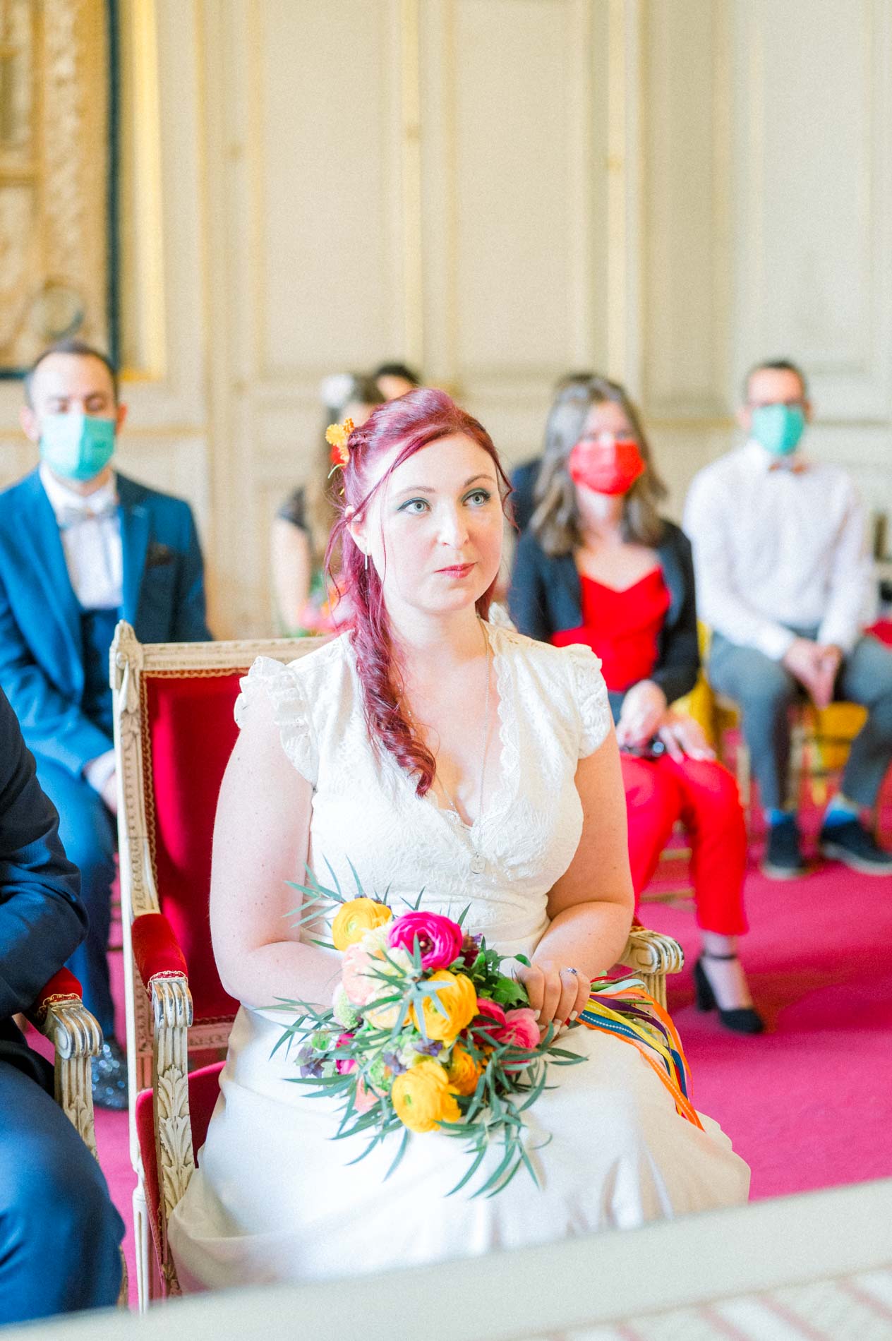 Bride seated during the civil ceremony with masked guests behind her