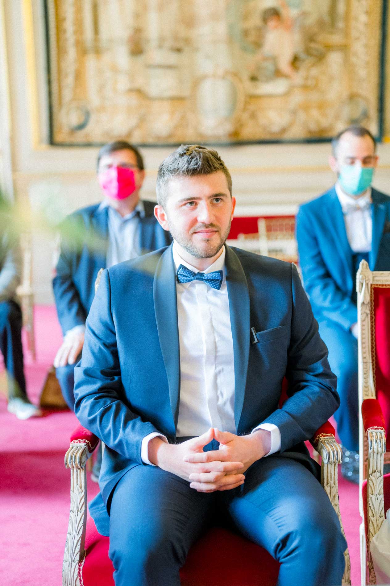 Groom seated in a red armchair during the city hall ceremony