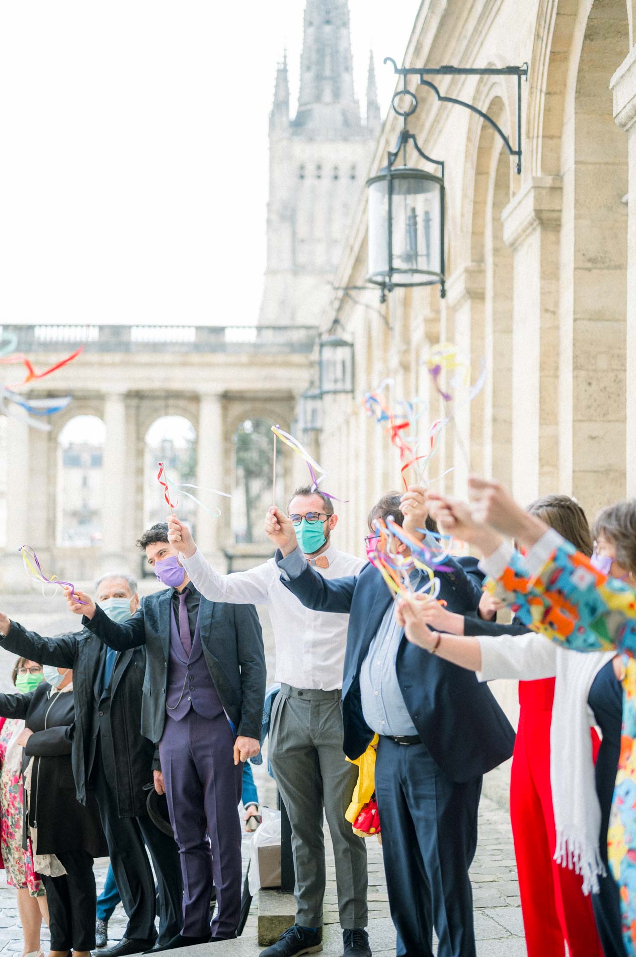 Guests waving colourful ribbons as the couple leave under the colonnade