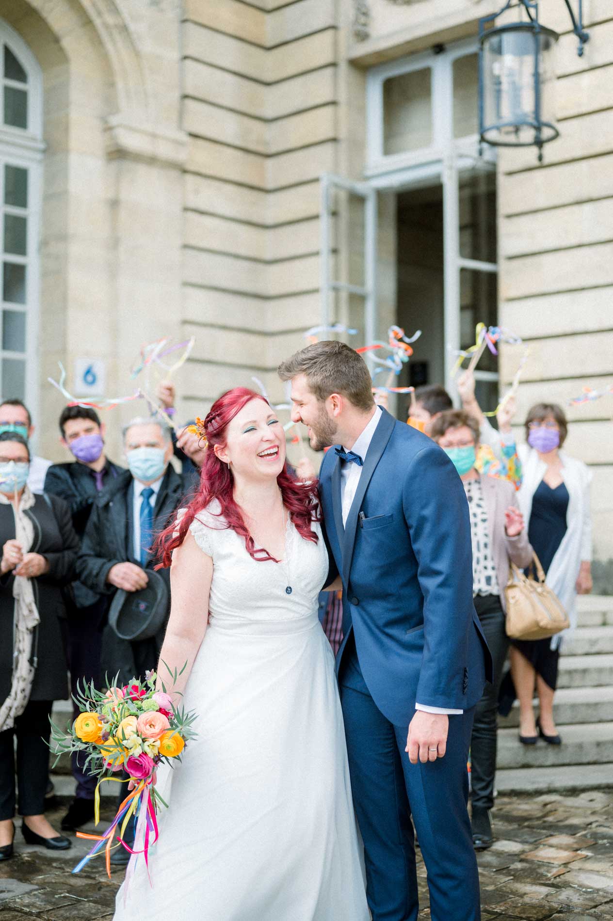 Beaming newlyweds walking down the steps under their guests' ribbons