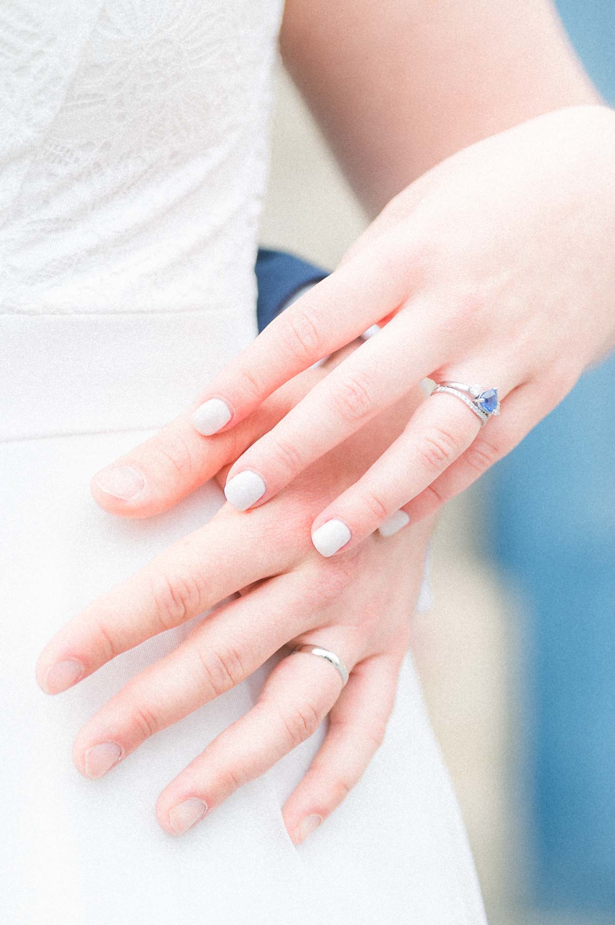 The couple's stacked hands showing wedding band and engagement ring