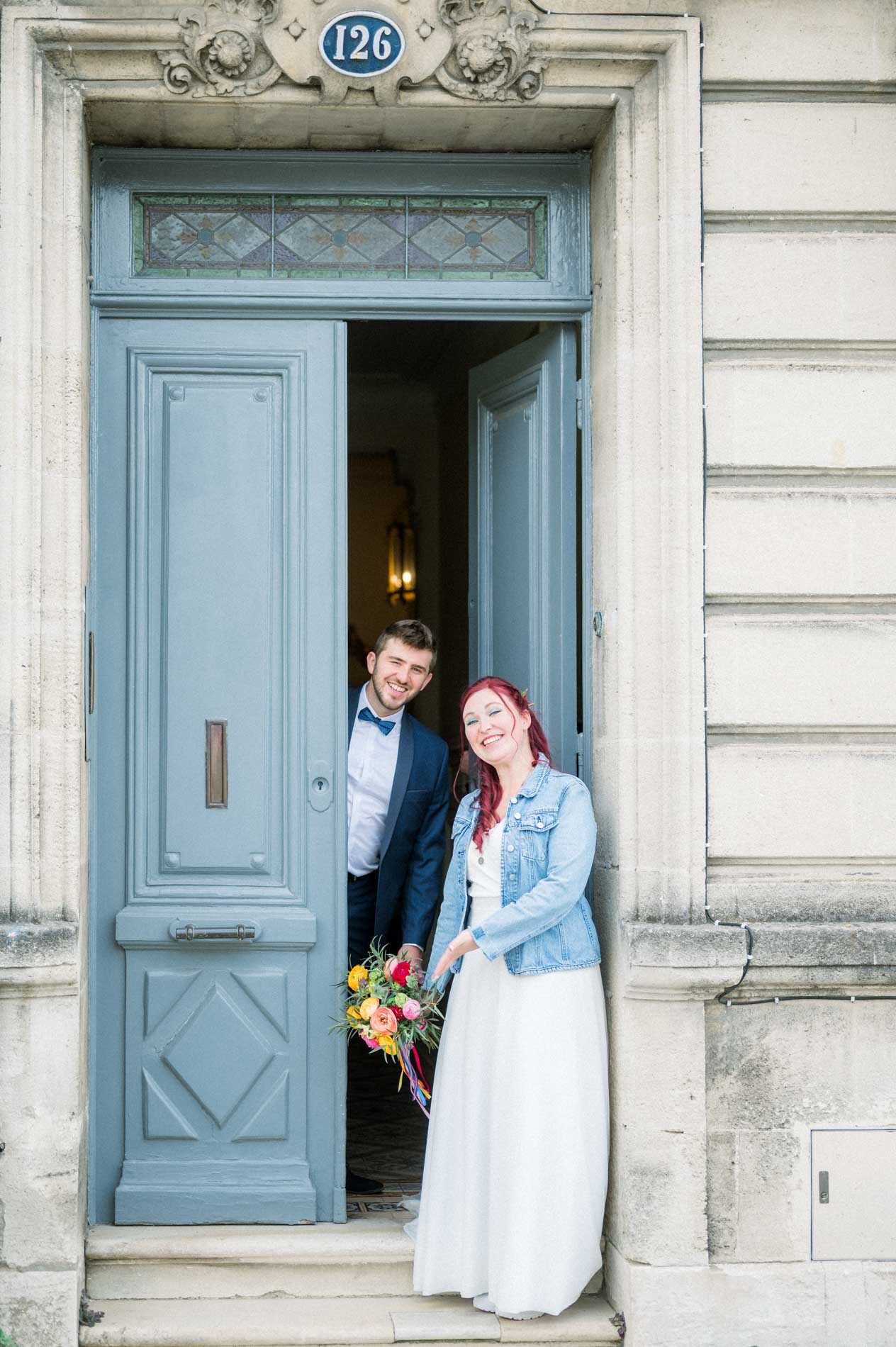 Smiling bride and groom framed in a tall blue doorway in town