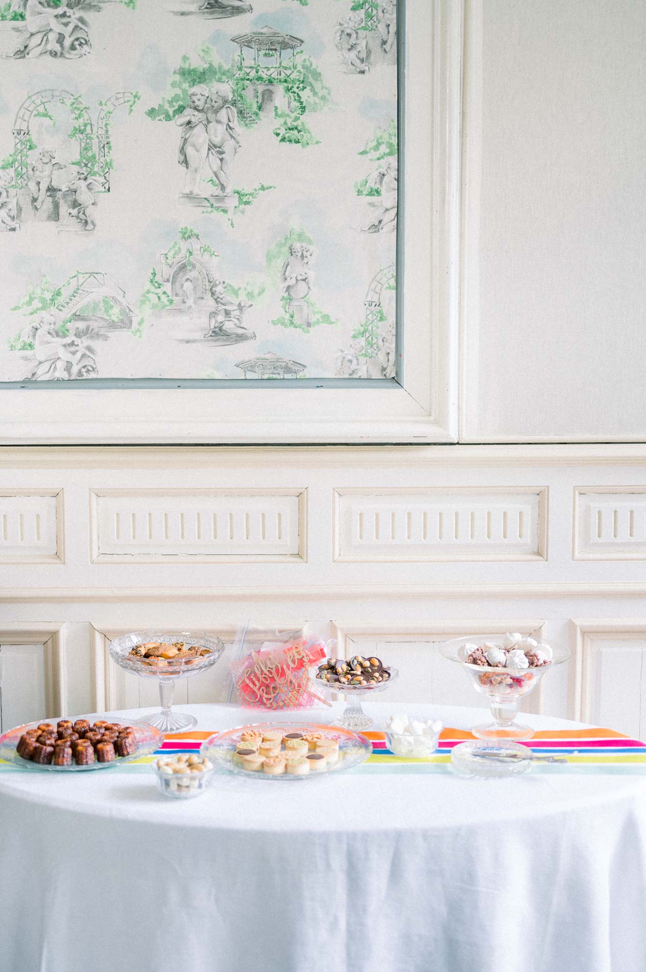 Sweet buffet on a white tablecloth against patterned wallpaper