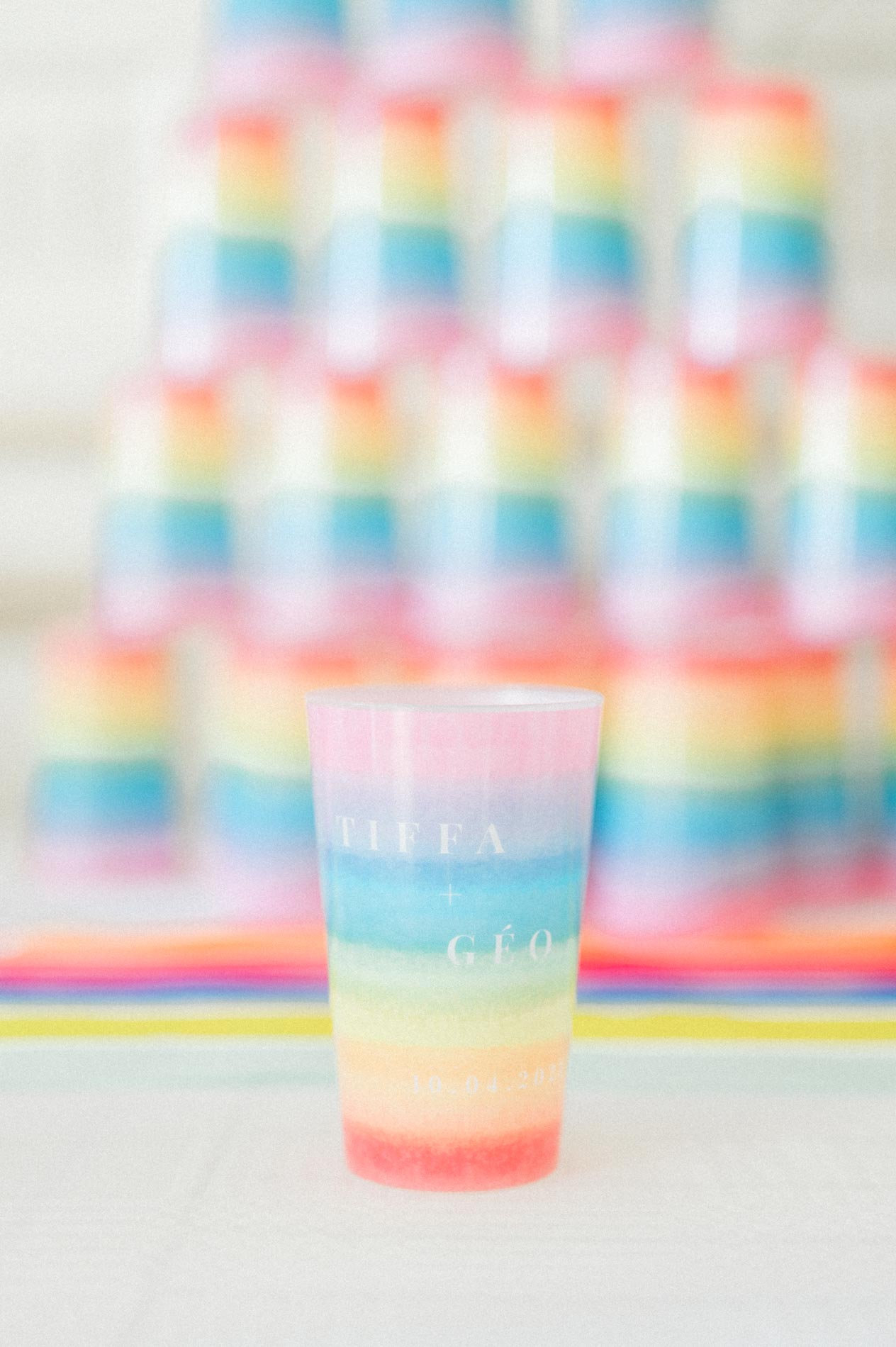 Personalised rainbow-coloured cups stacked on the buffet