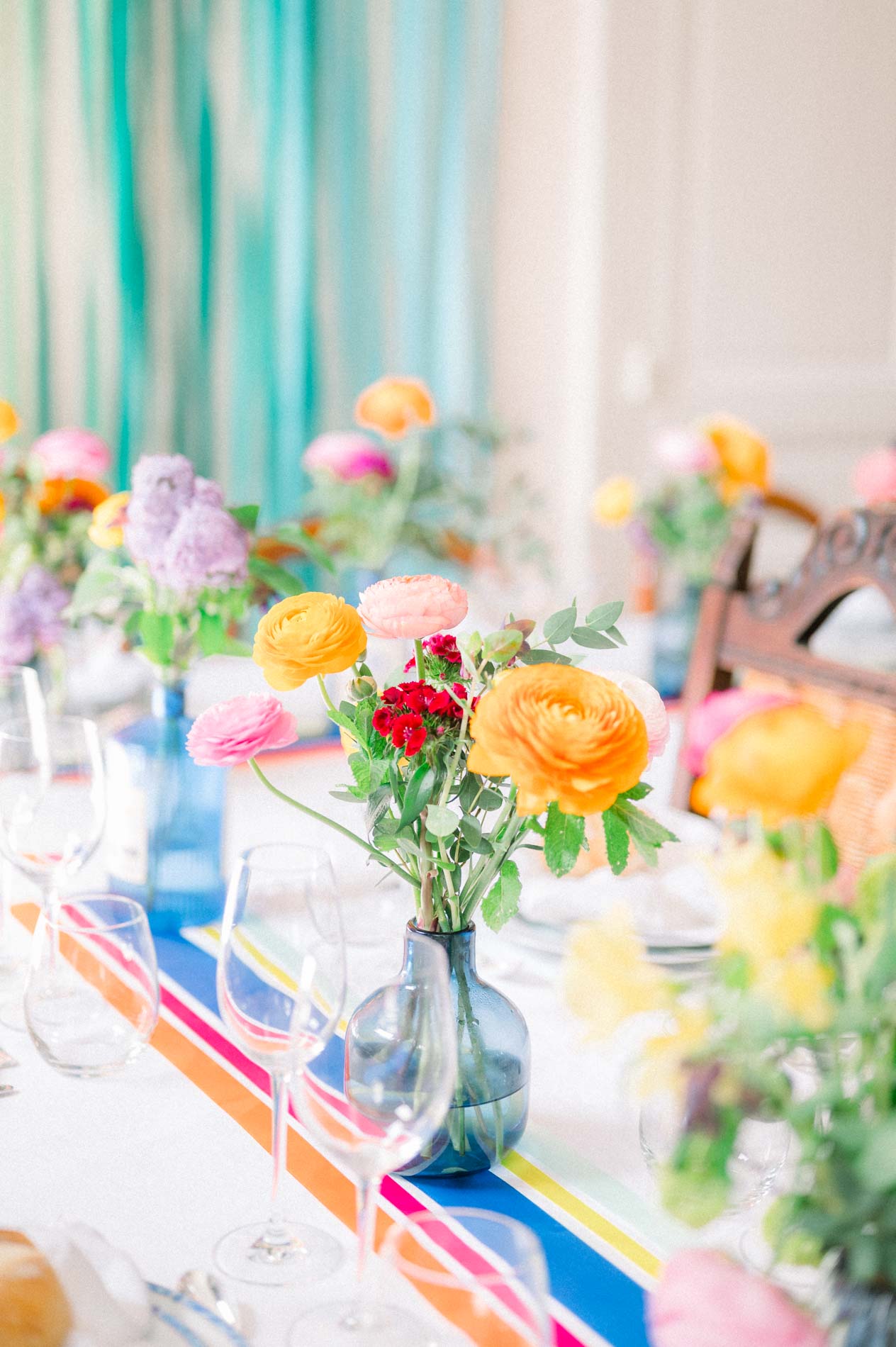 Reception table decorated with bright flowers and a striped runner