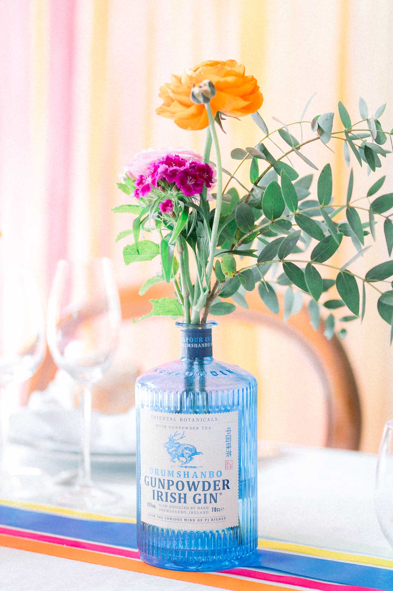 Orange ranunculus and anemone in a blue glass bottle