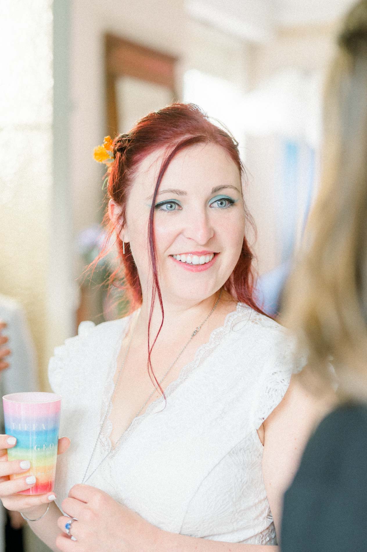 Smiling bride holding a rainbow cup during the reception