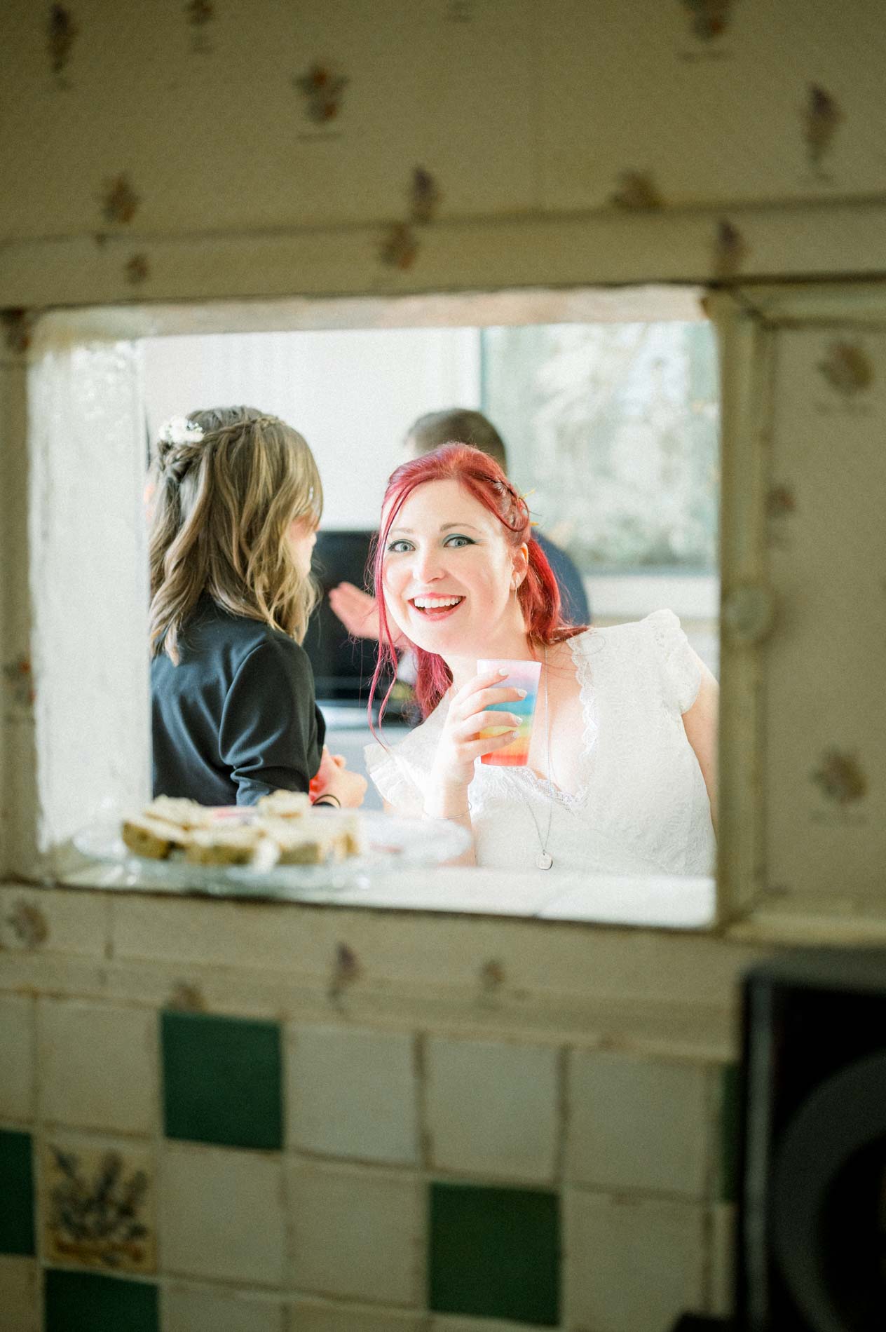 Smiling bride glimpsed through a serving hatch with her guests