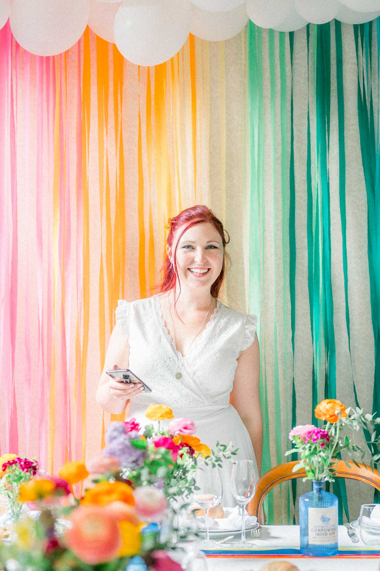 Bride before a curtain of multicoloured ribbons and a flower-filled table