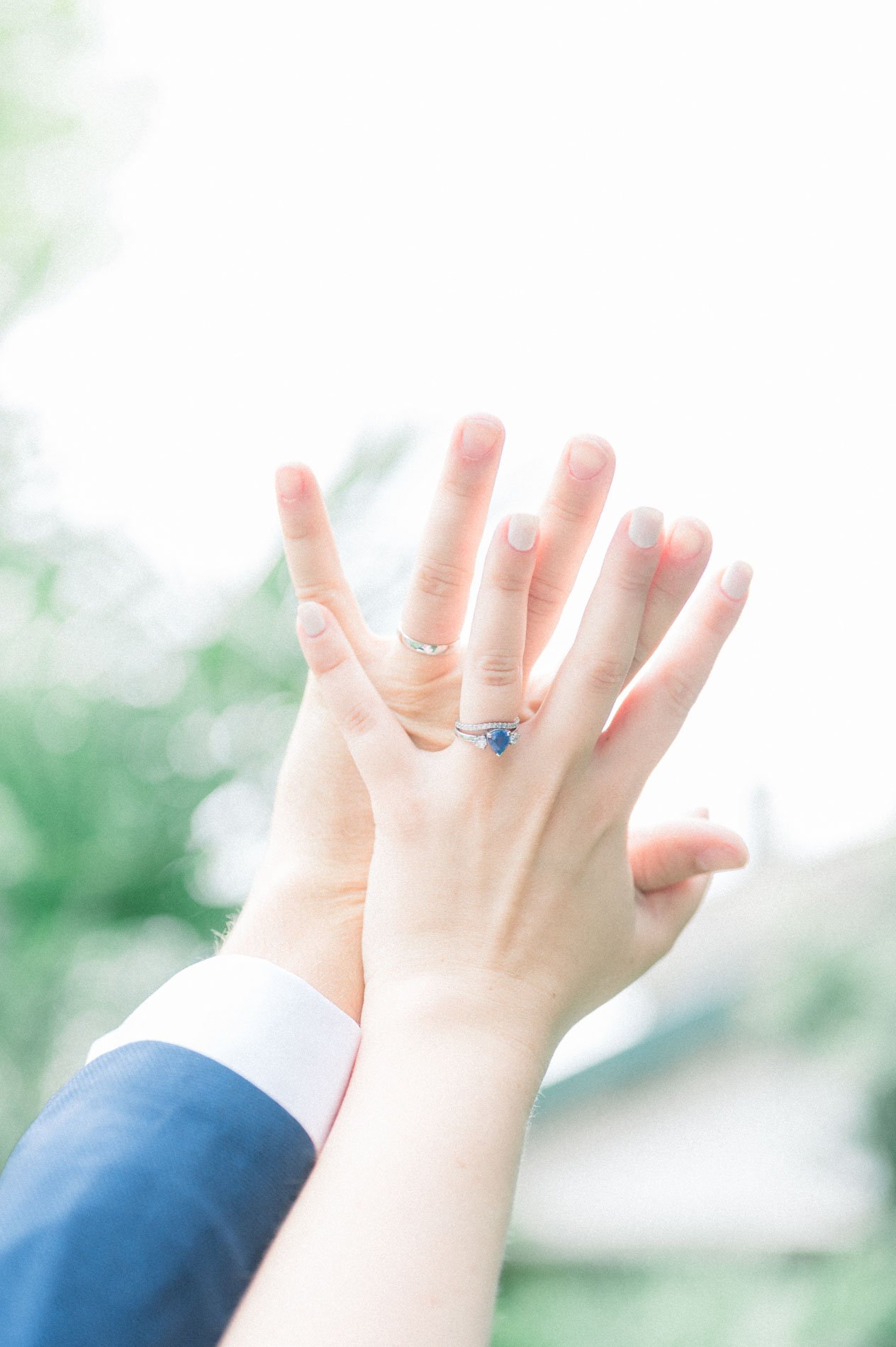 The couple's hands touching, showing the sapphire engagement ring