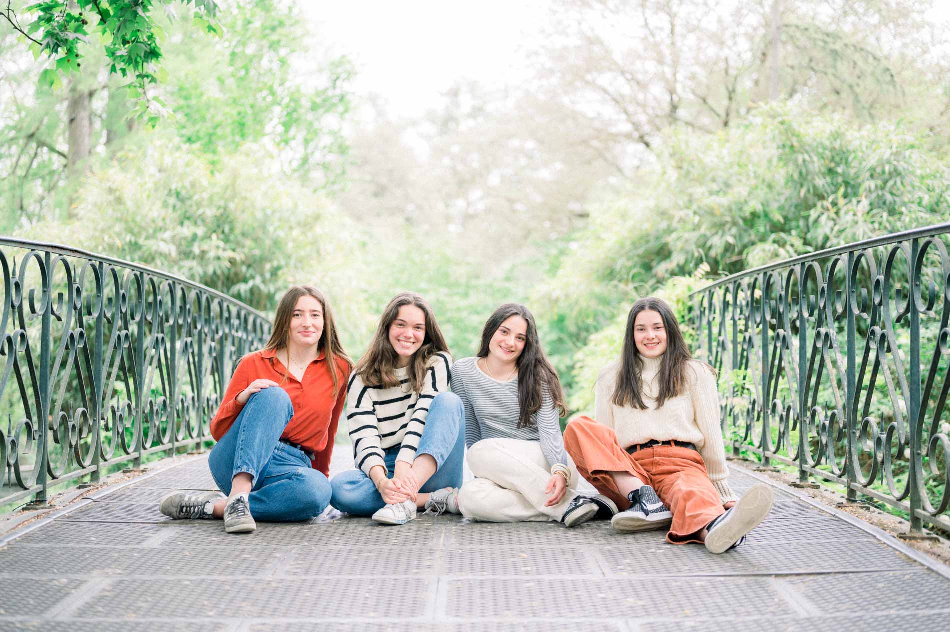 Four friends sitting on the wrought-iron footbridge in the Jardin Public, Bordeaux