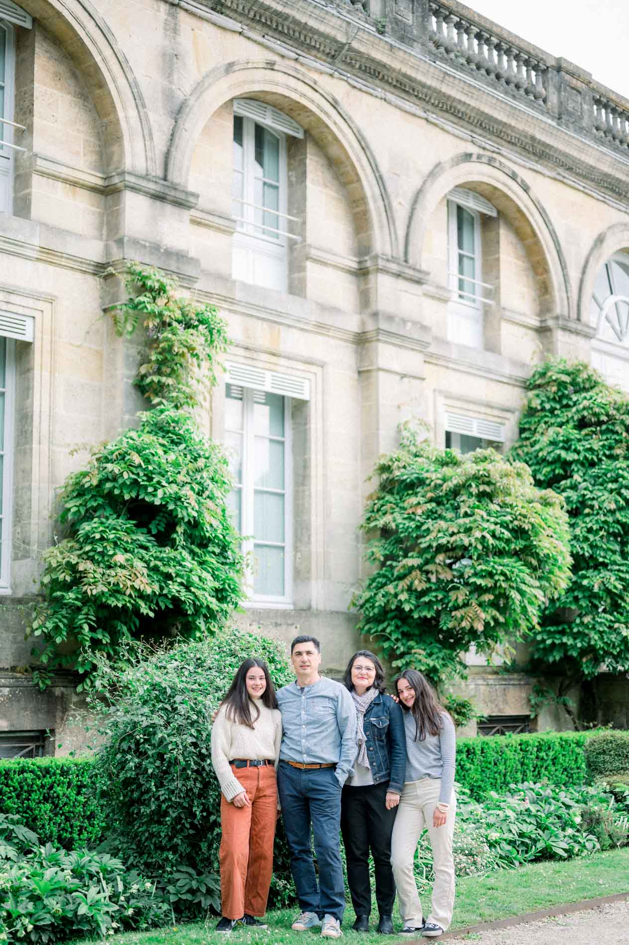 Portrait de famille devant la façade à arcades couverte de lierre du Jardin Public