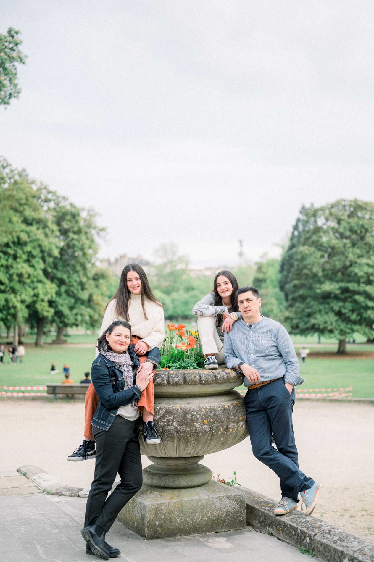 Famille complice autour d'une grande vasque en pierre dans le jardin