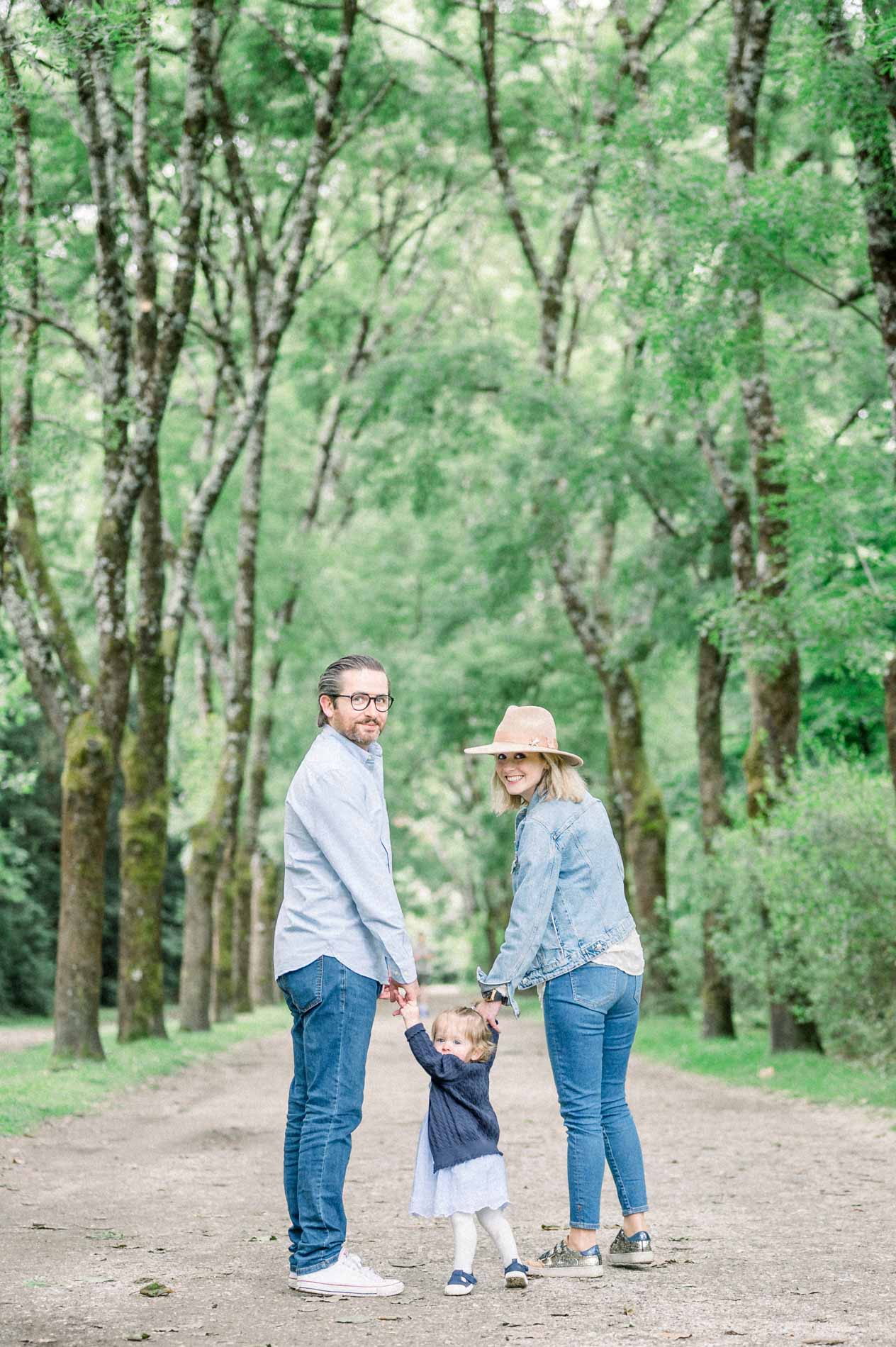 The parents holding their daughter's hands on a path in Parc Bordelais