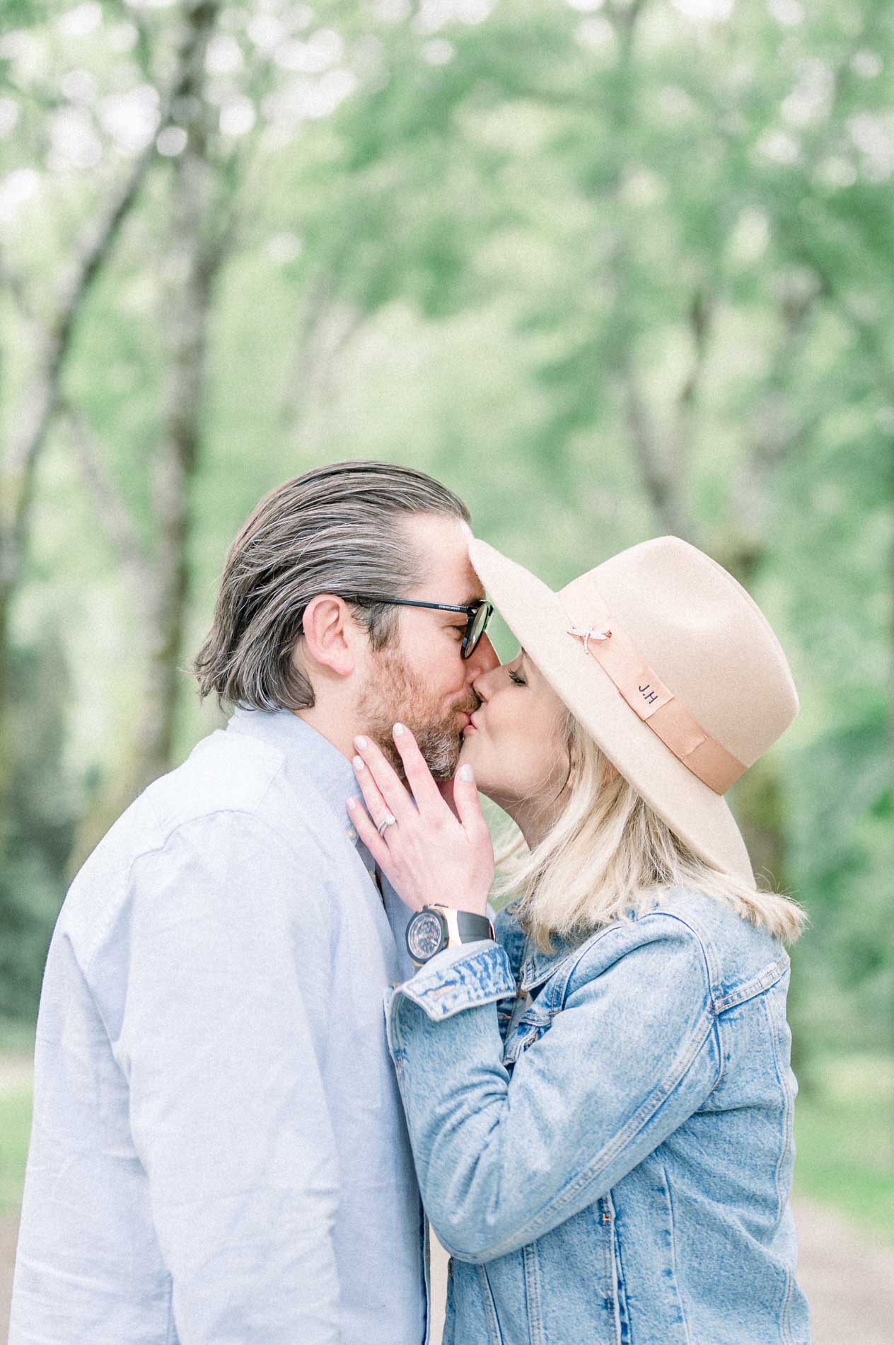 The parents sharing a tender kiss beneath the trees of Parc Bordelais