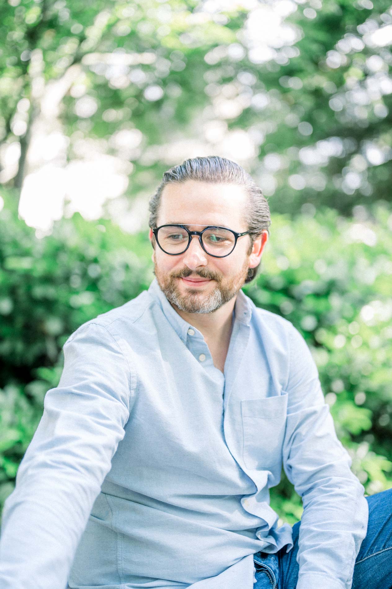 Portrait of the father in glasses and a pale blue shirt amid greenery