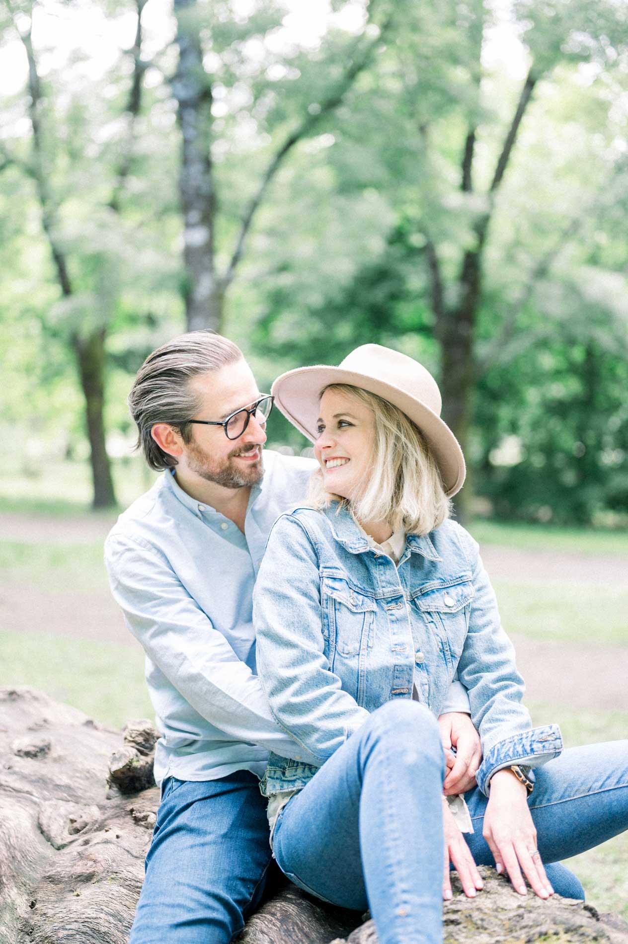 The parents sitting close together on the tree trunk, sharing a smile