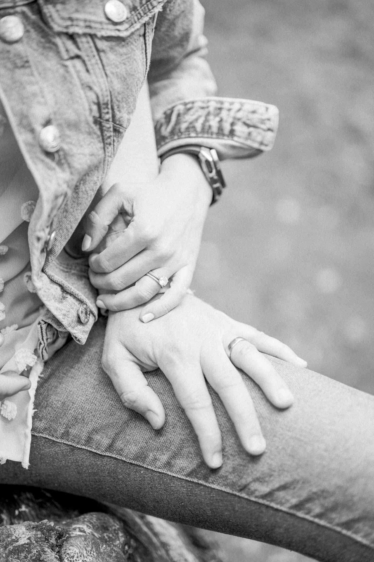 The parents' hands intertwined on a knee, in black and white