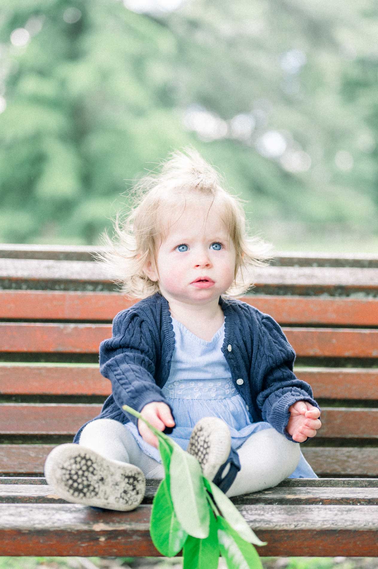 The little girl on the bench holding a green leaf