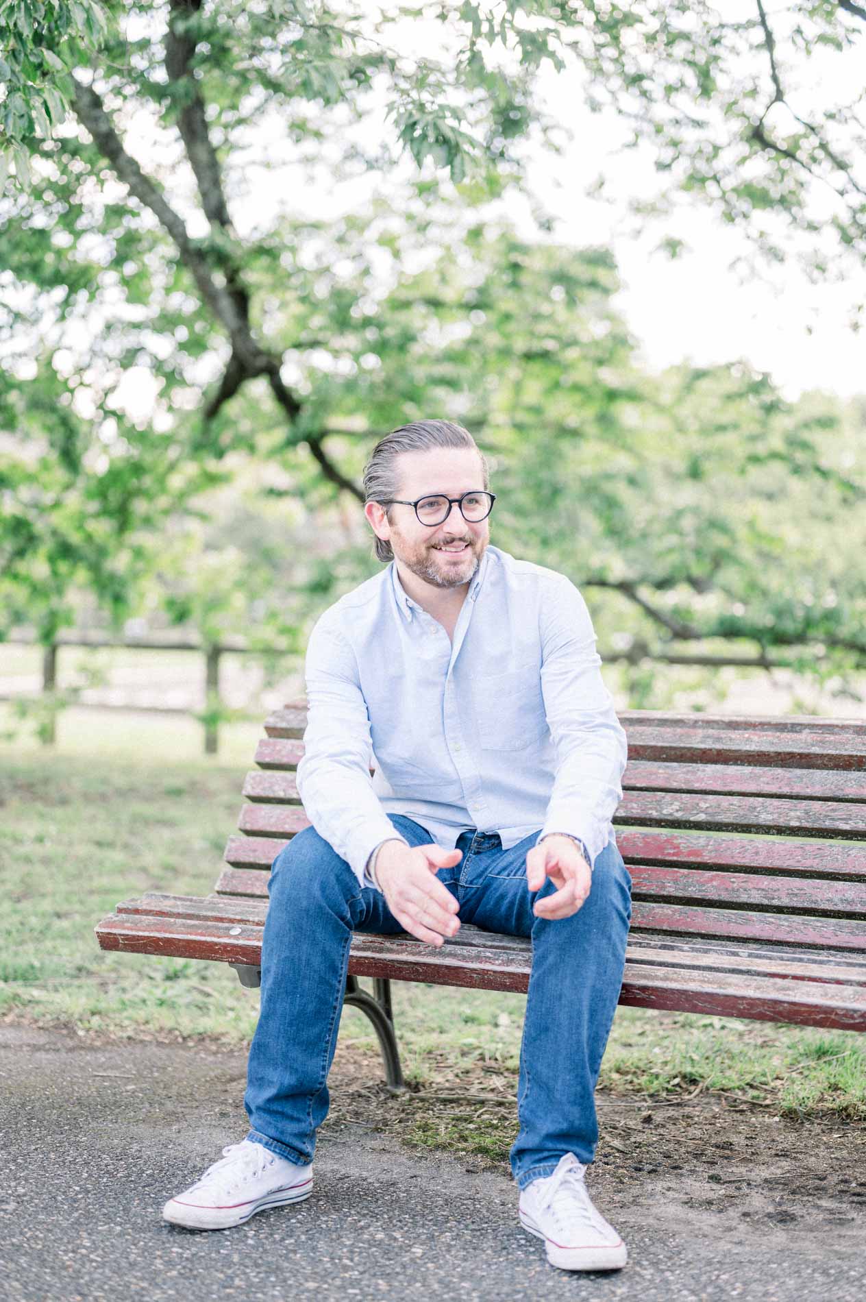 The smiling father sitting alone on a wooden park bench