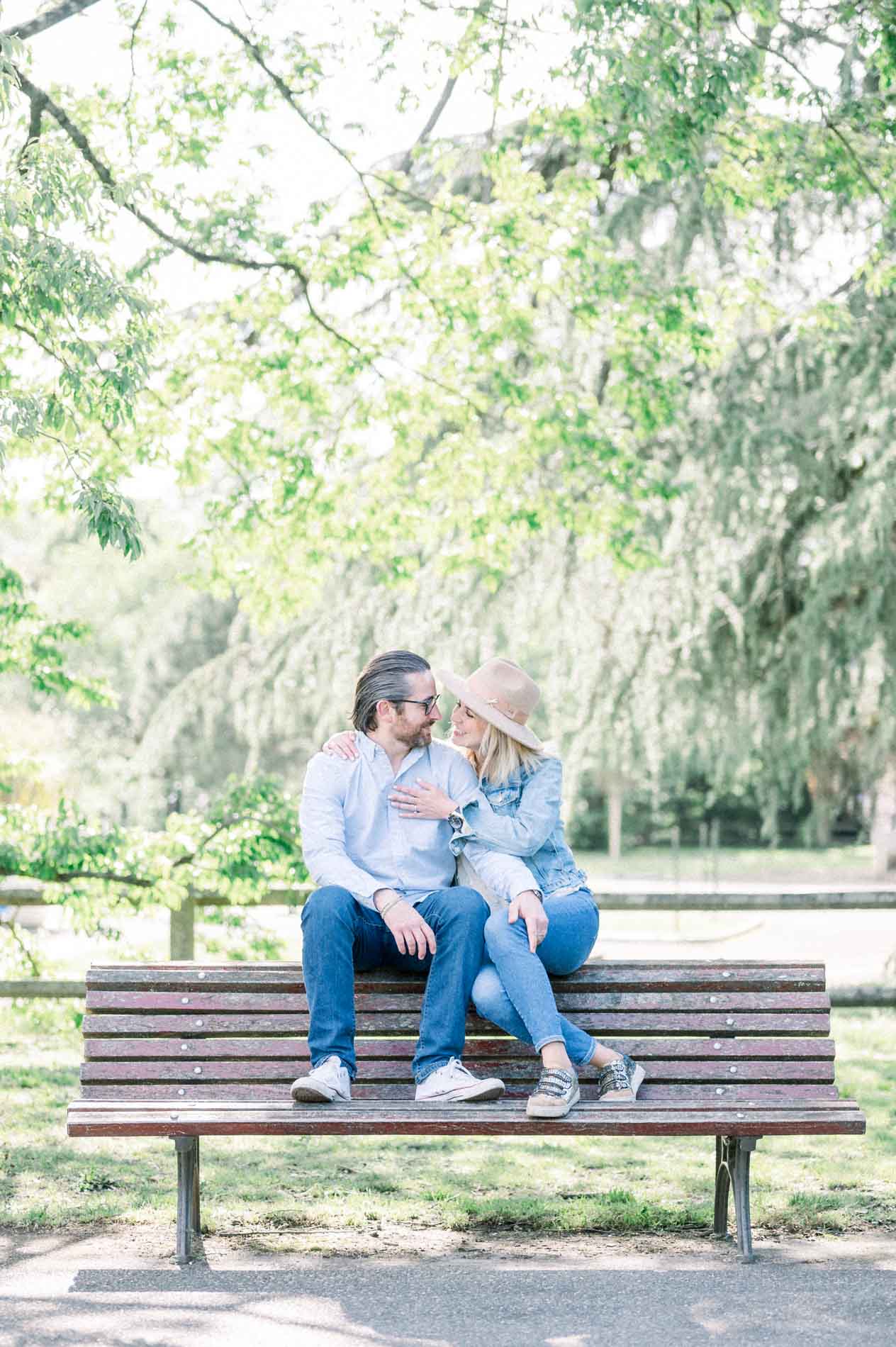 The parents cuddled up on a bench in front of a weeping willow