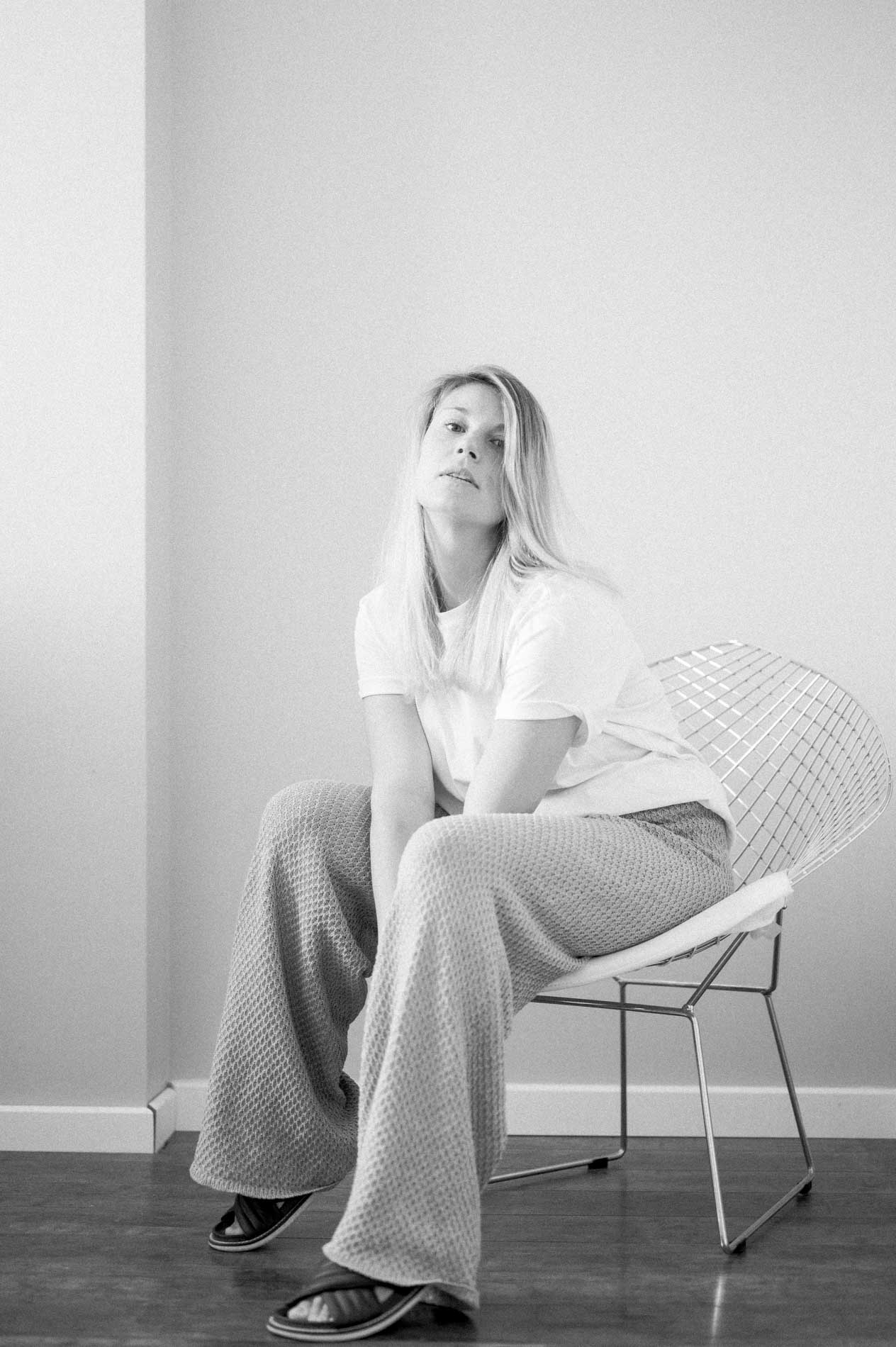 Model seated on a wire chair in wide-leg trousers, black and white
