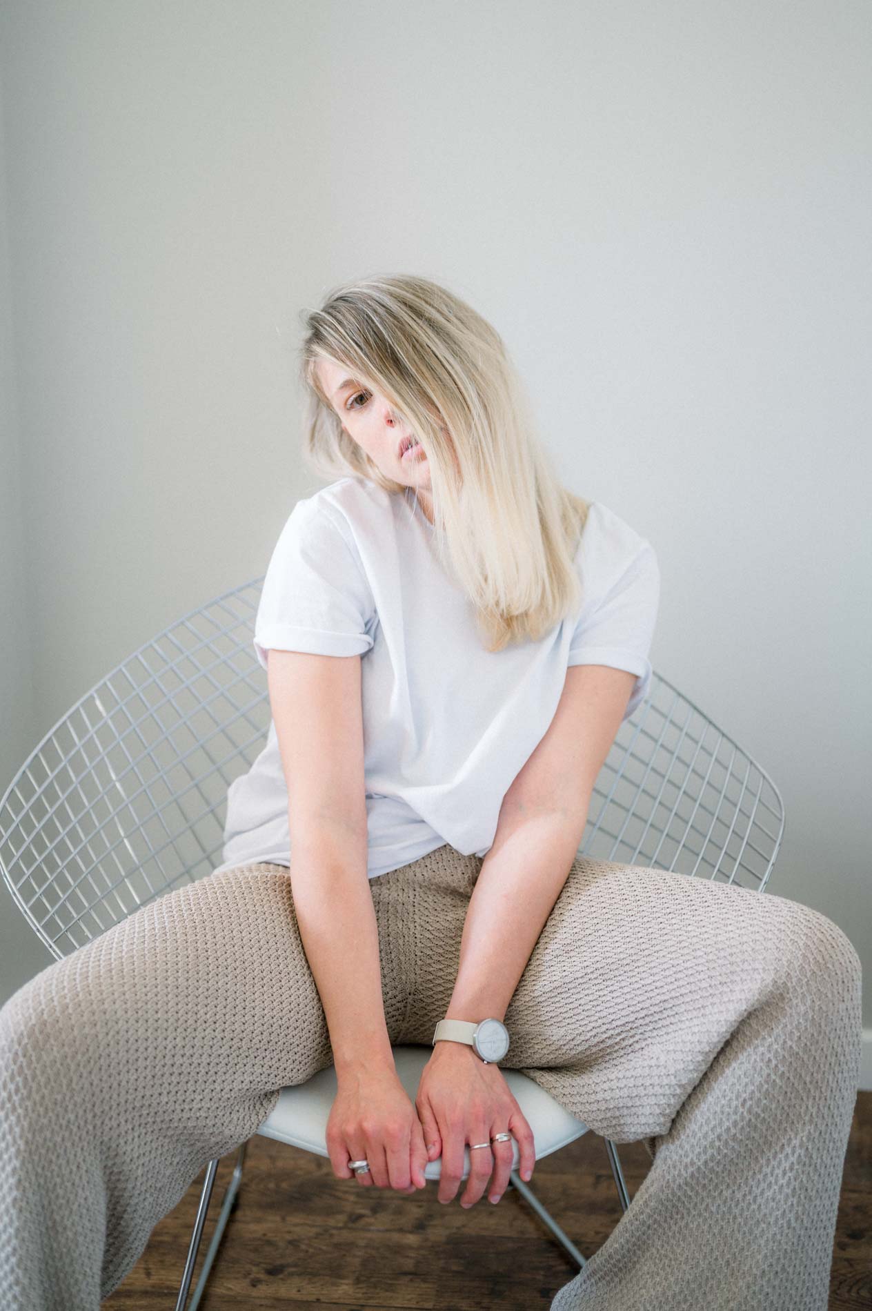 Blonde model sitting on a wire chair, looking down