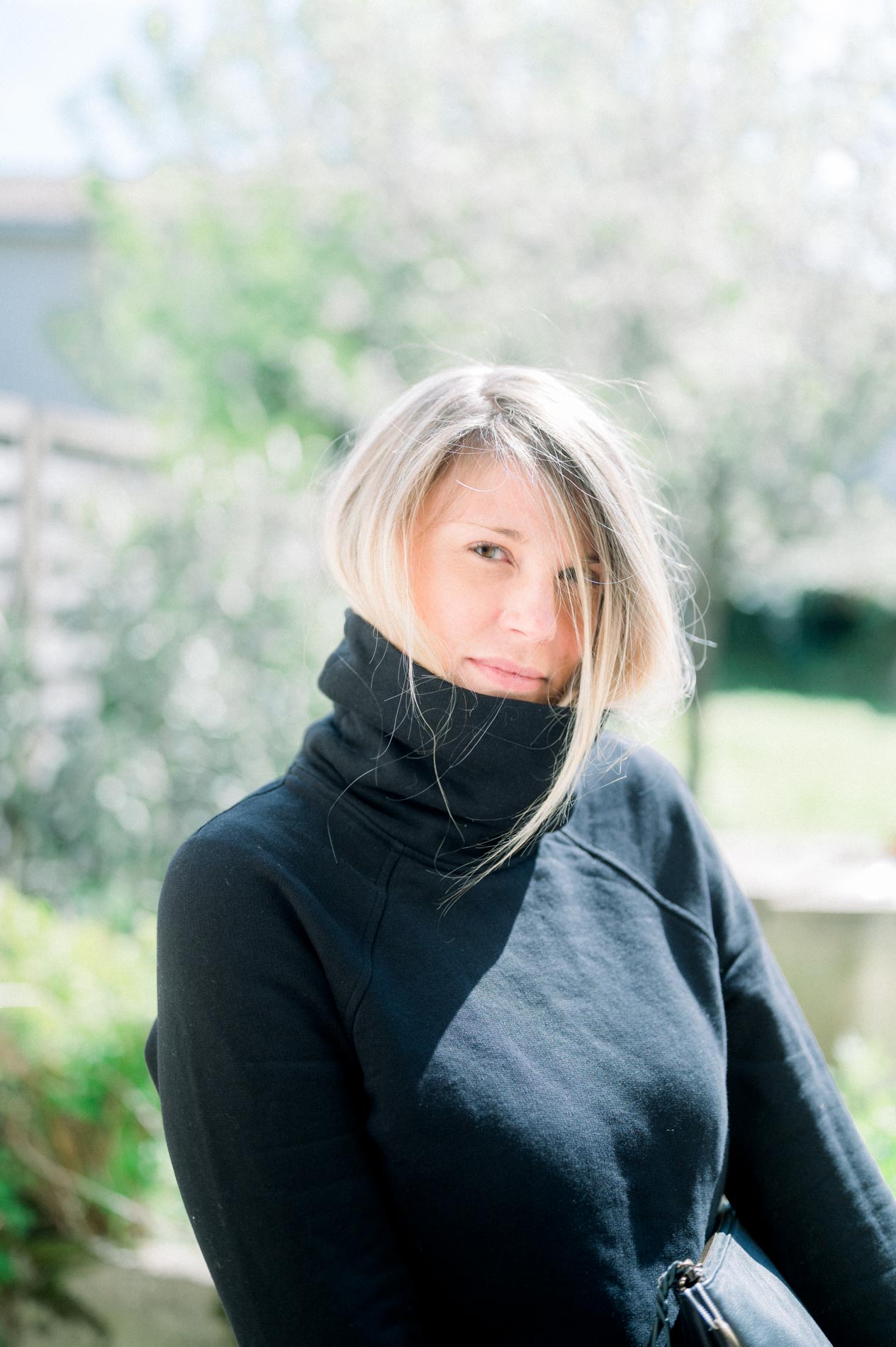 Model in a black roll-neck jumper in a garden, natural light