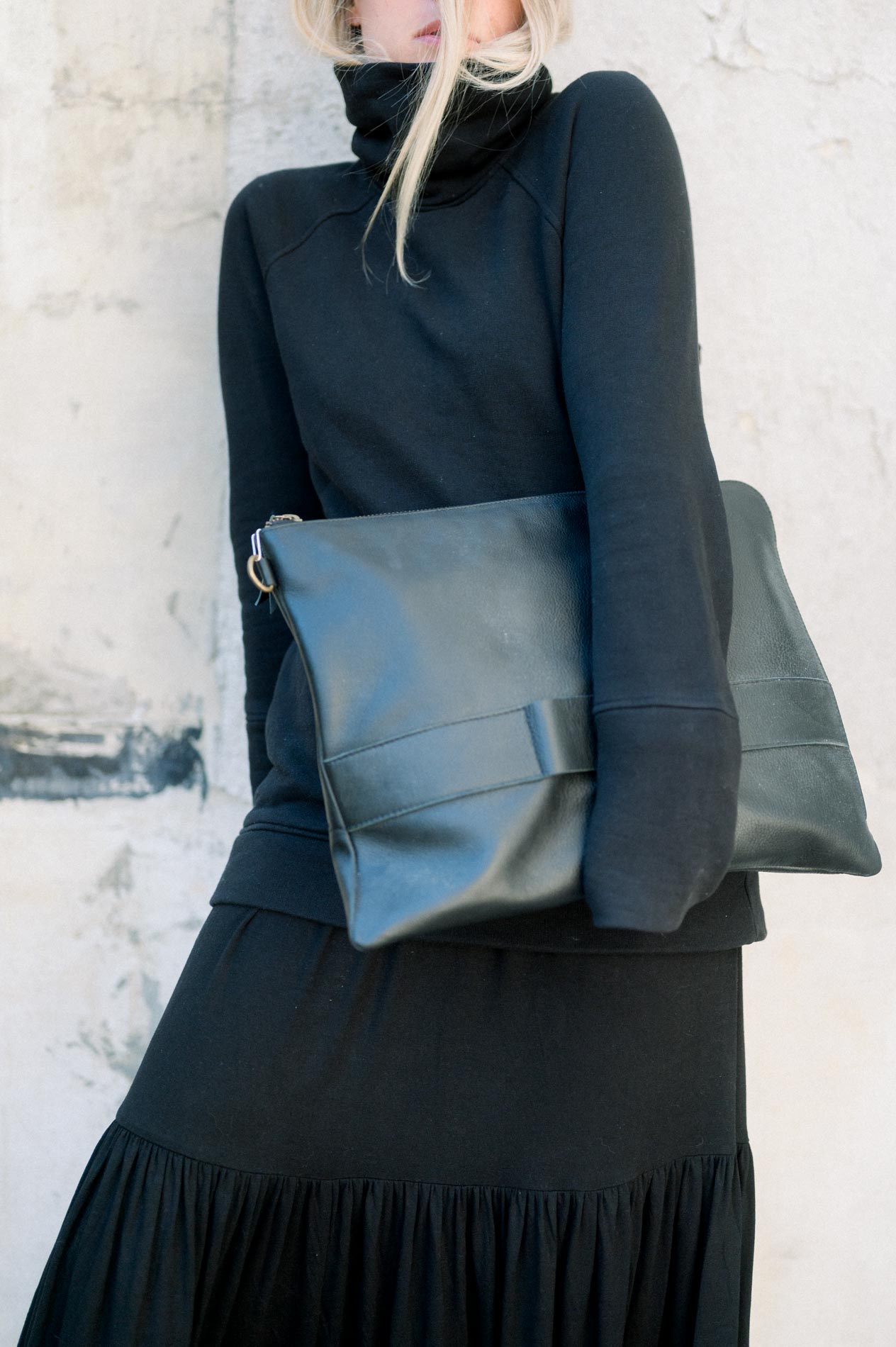 Detail of a black leather clutch worn with a long black dress