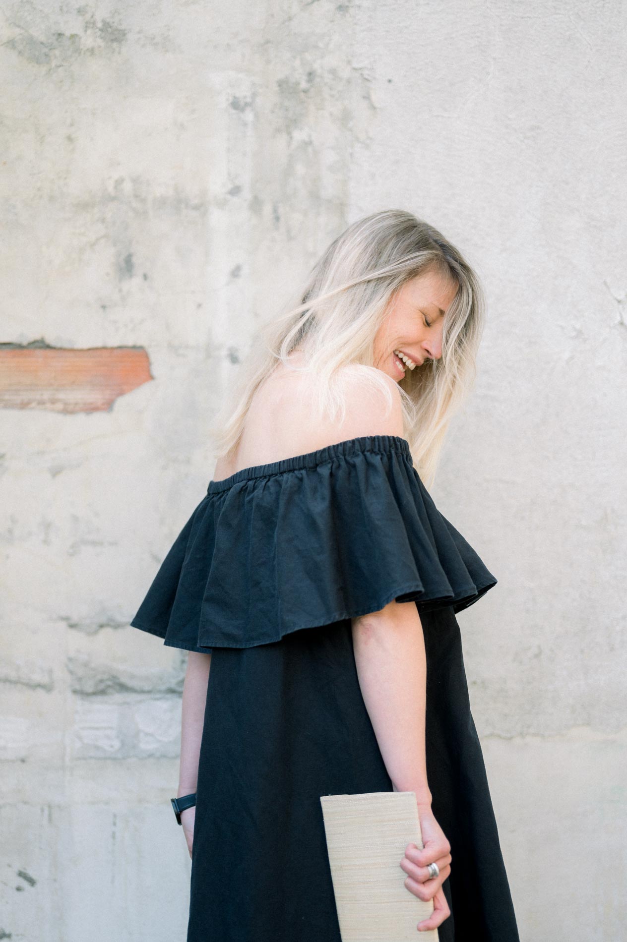 Model in profile in a black ruffled dress, book in hand