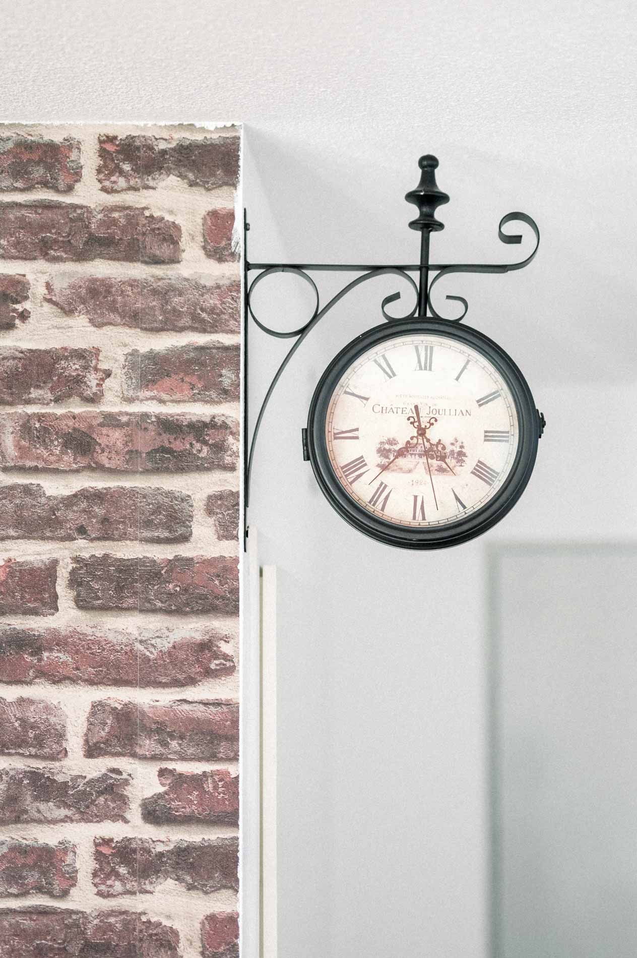 Wrought-iron station clock on a brick wall at home