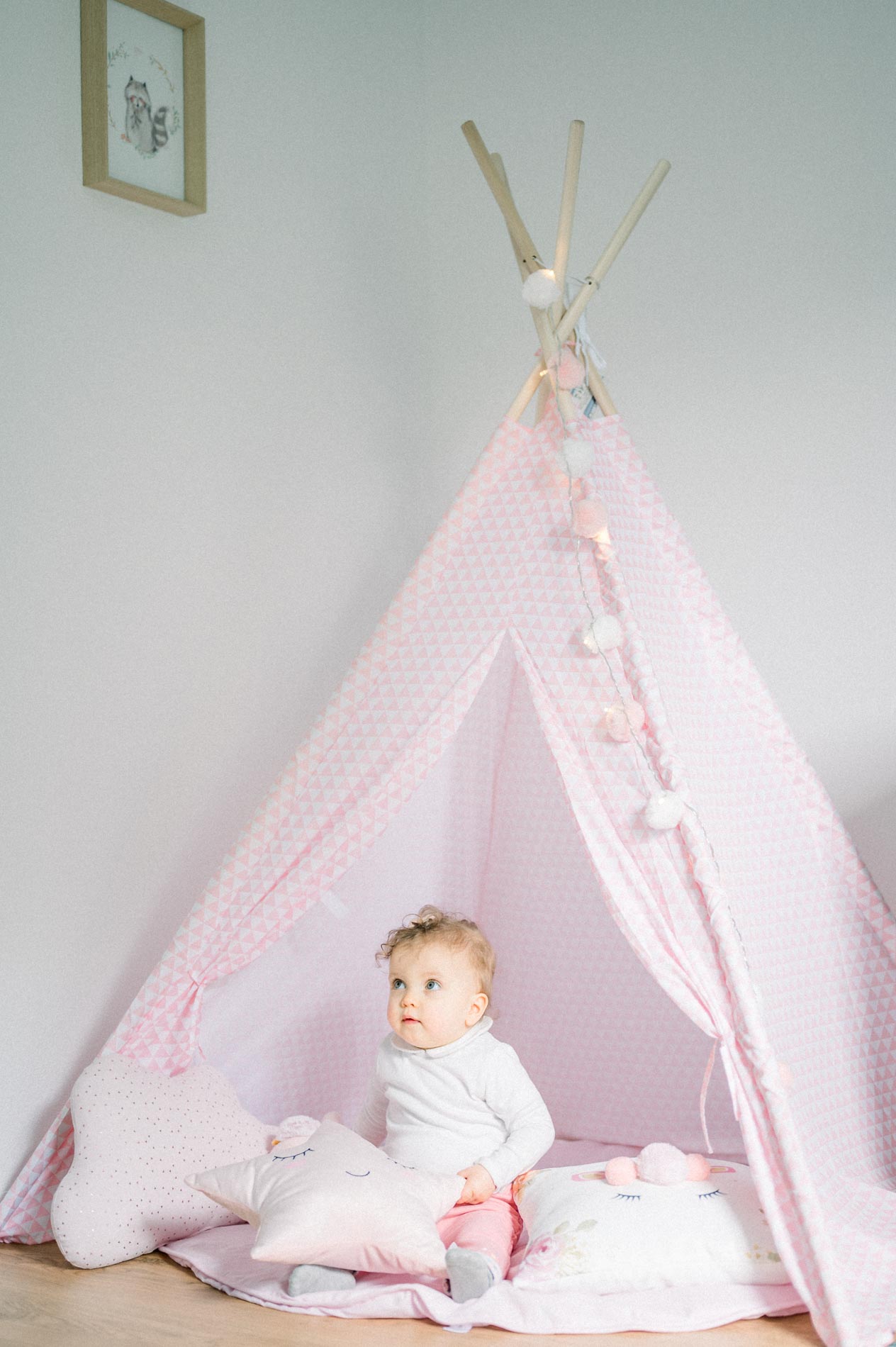 Baby sitting in a pink teepee filled with cushions
