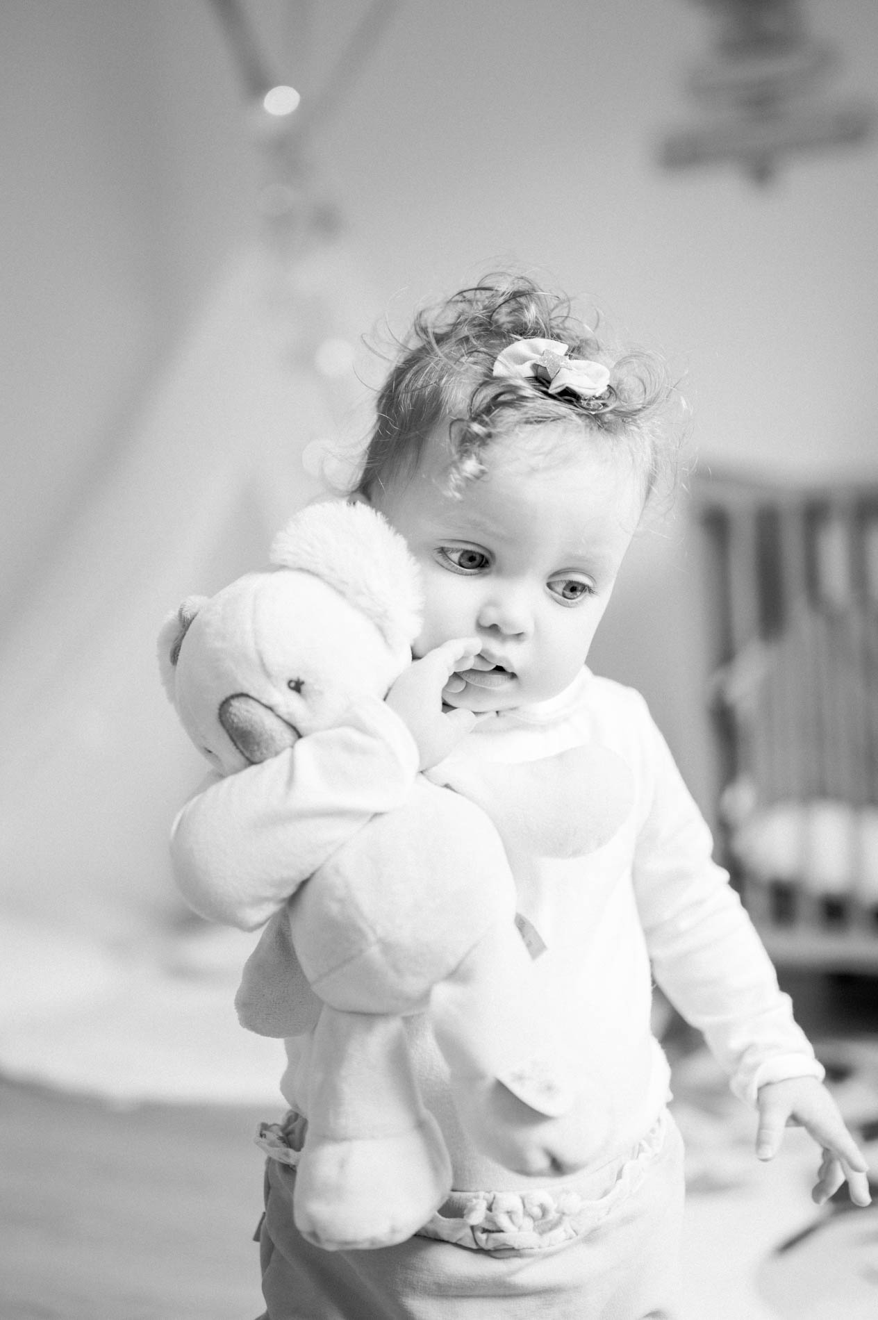Baby hugging a soft toy in the nursery, in black and white