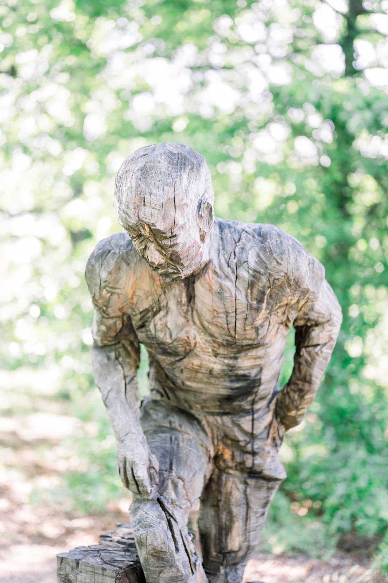 Carved wooden statue of a crouching man at Domaine de Pinsan