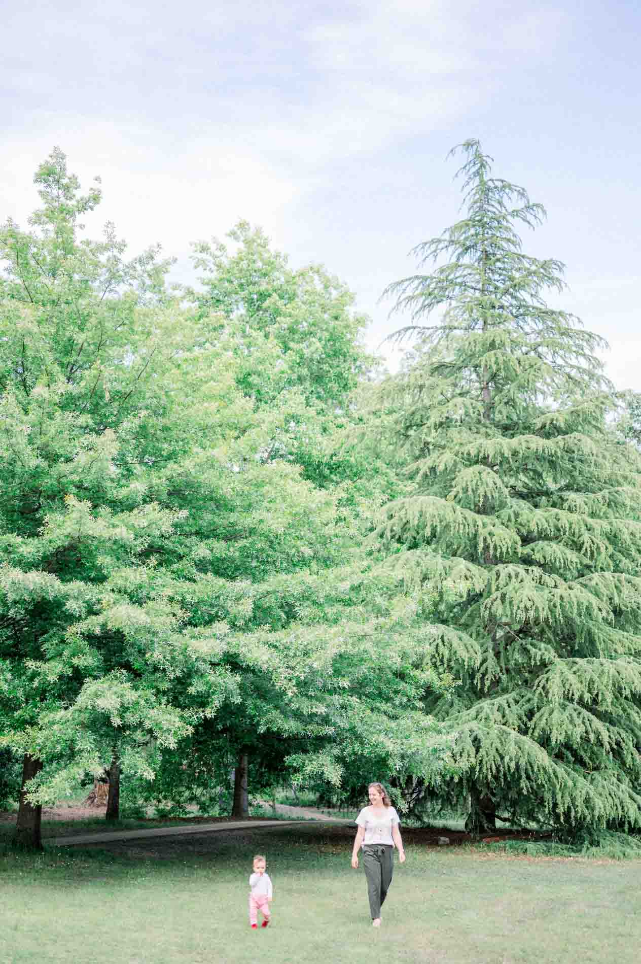 Mum and child walking at the foot of the park's tall trees