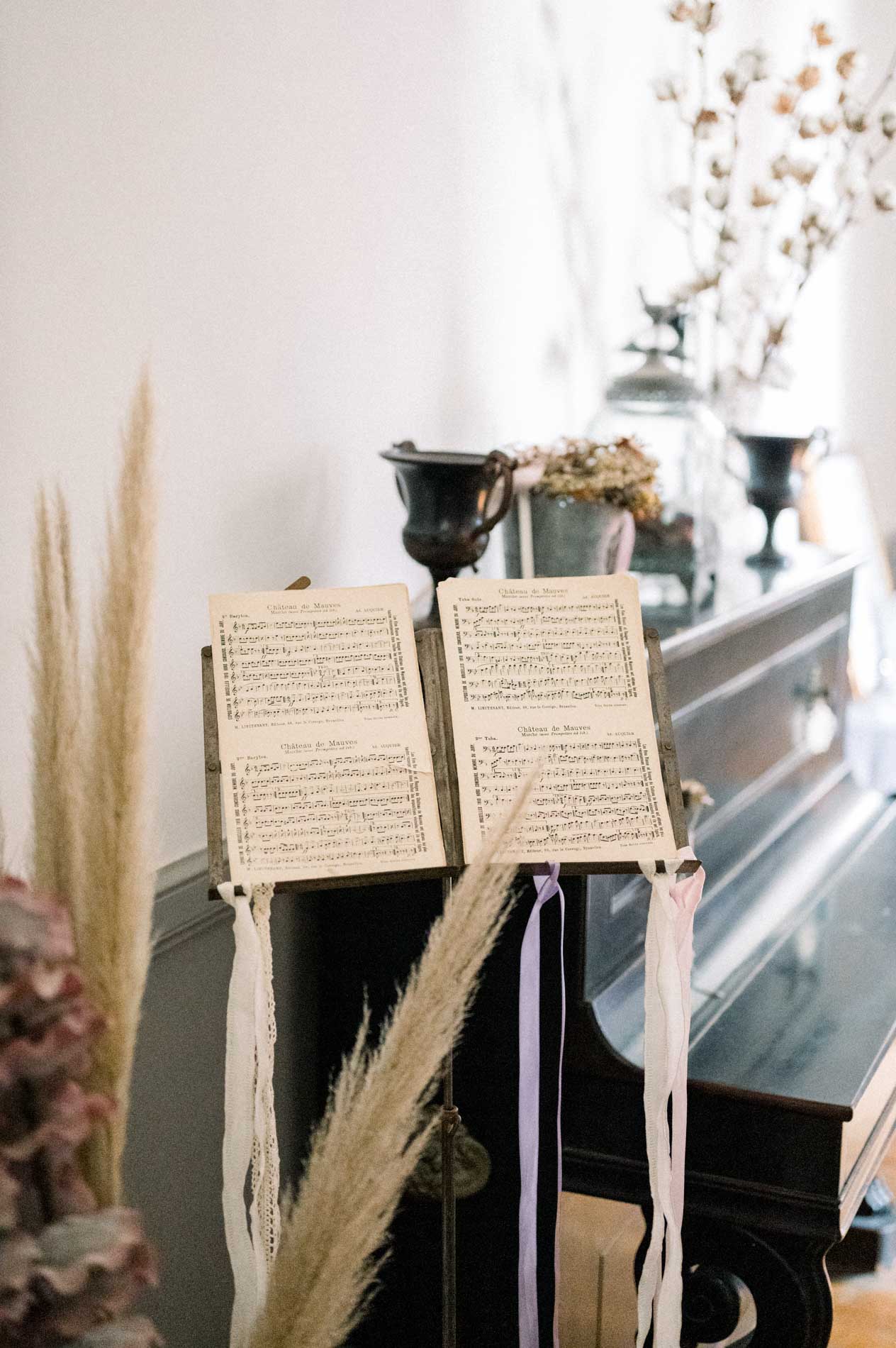 Open sheet music on a piano decorated with pampas grass in a lounge