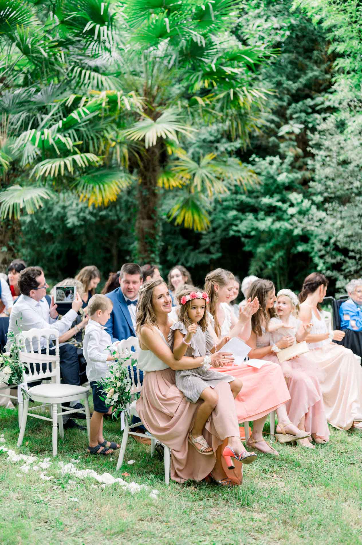 Guests seated under palm trees during the outdoor ceremony at Chartreuse des Eyres