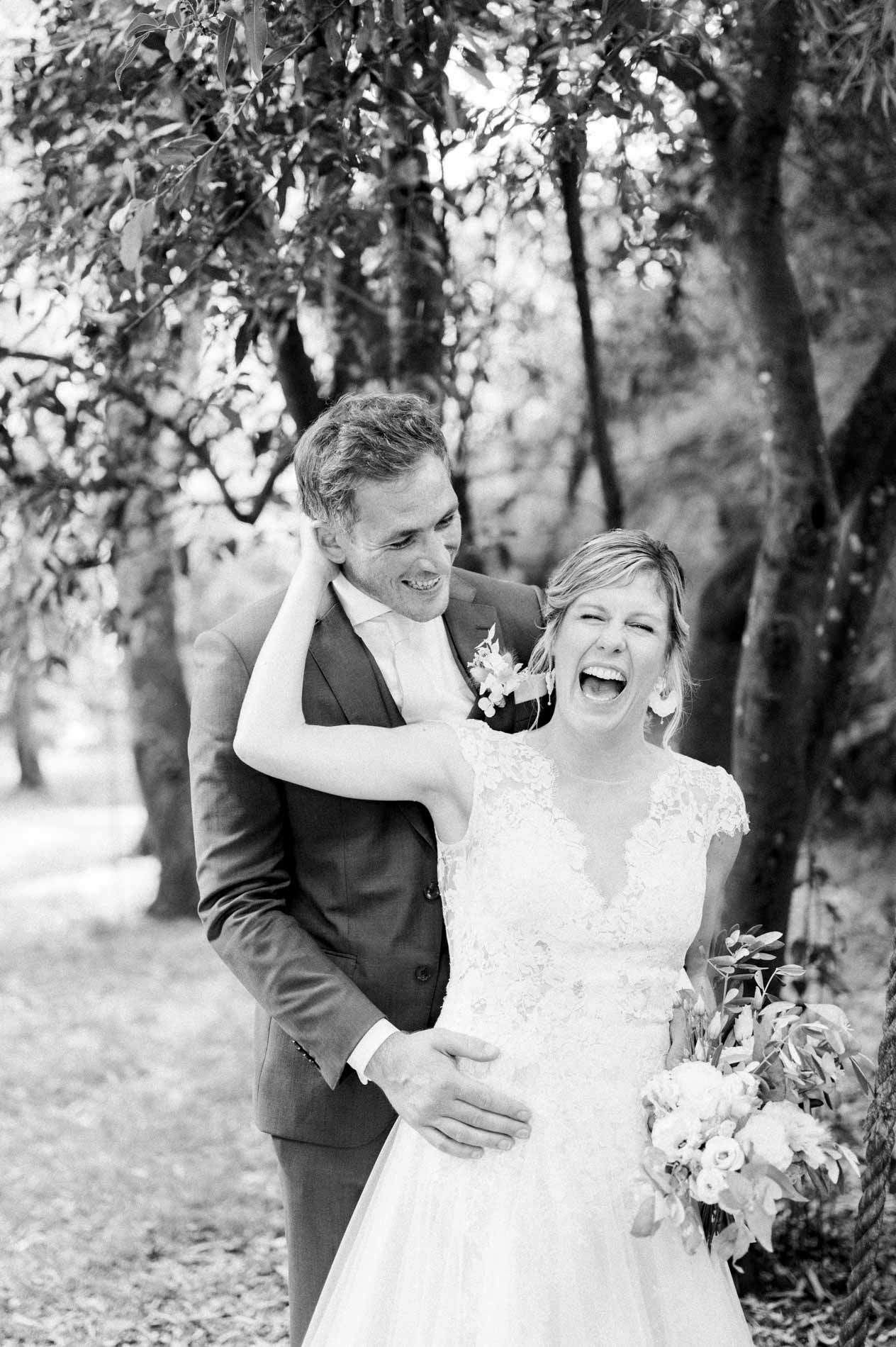 Bride laughing in the groom's arms, black and white photo