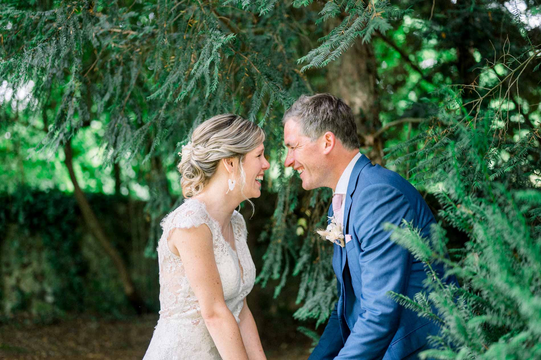 Bride and groom smiling at each other beneath the branches at Chartreuse des Eyres