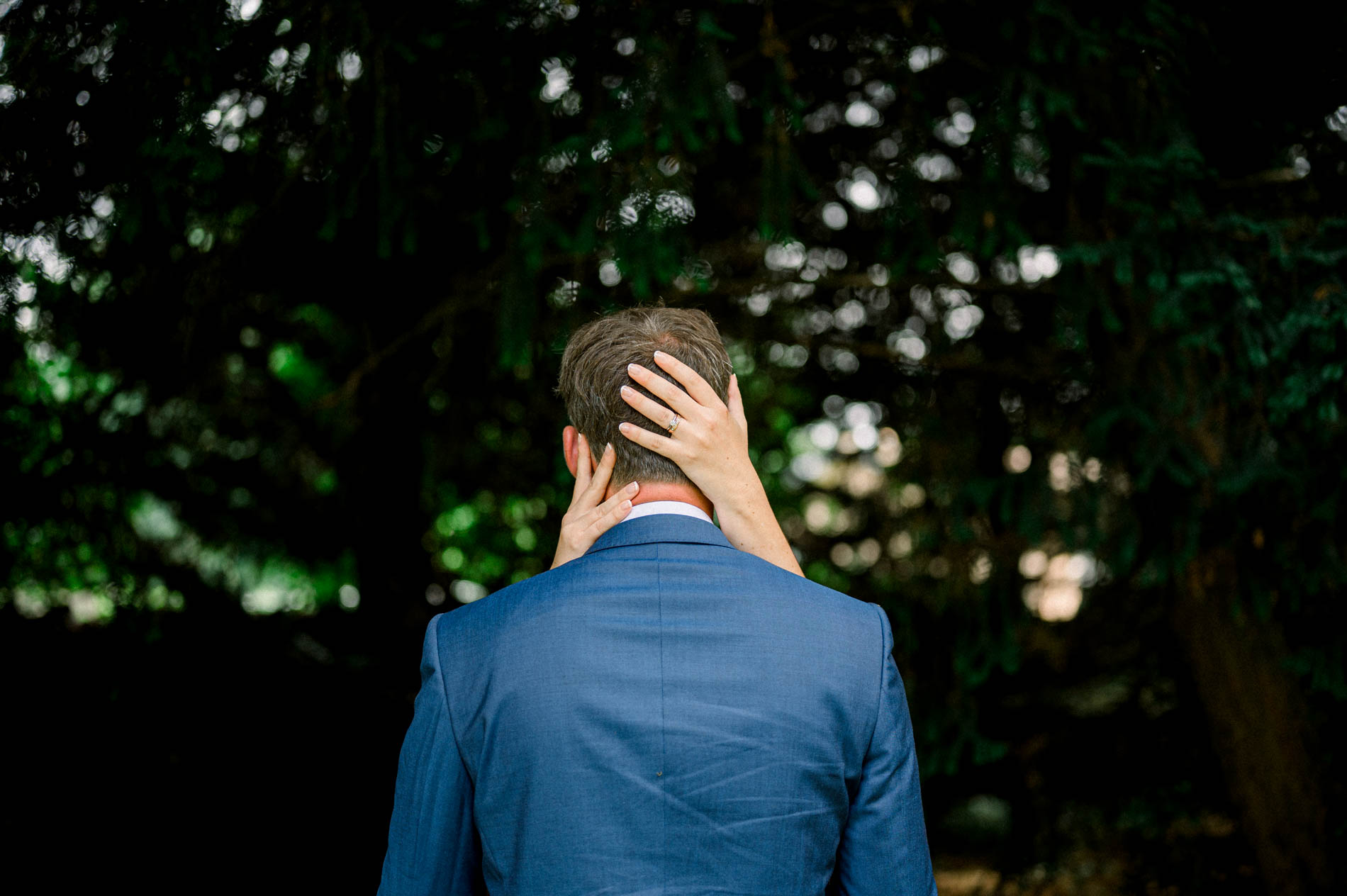 Bride's hand on the back of the groom's neck, seen from behind