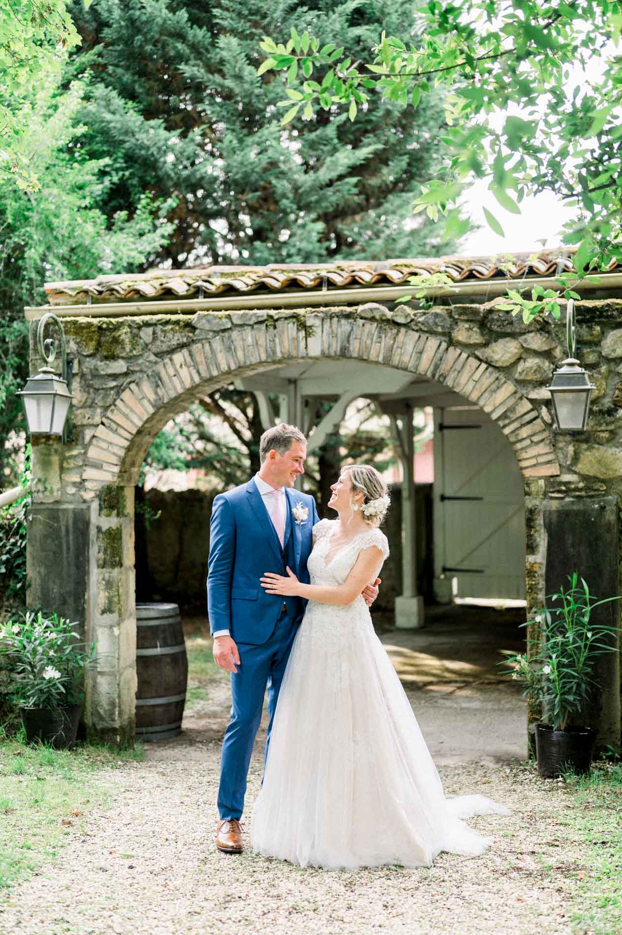 Bride and groom embracing beneath the tiled stone archway