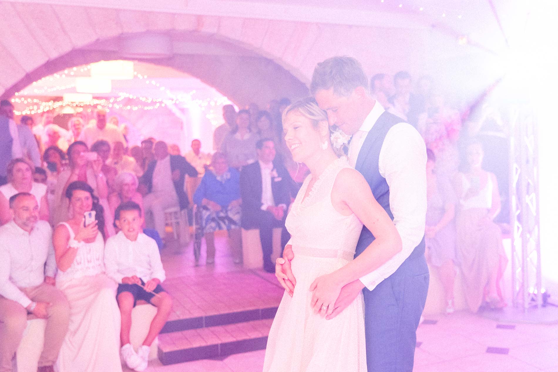 Bride and groom's first dance under pink lights in the vaulted hall