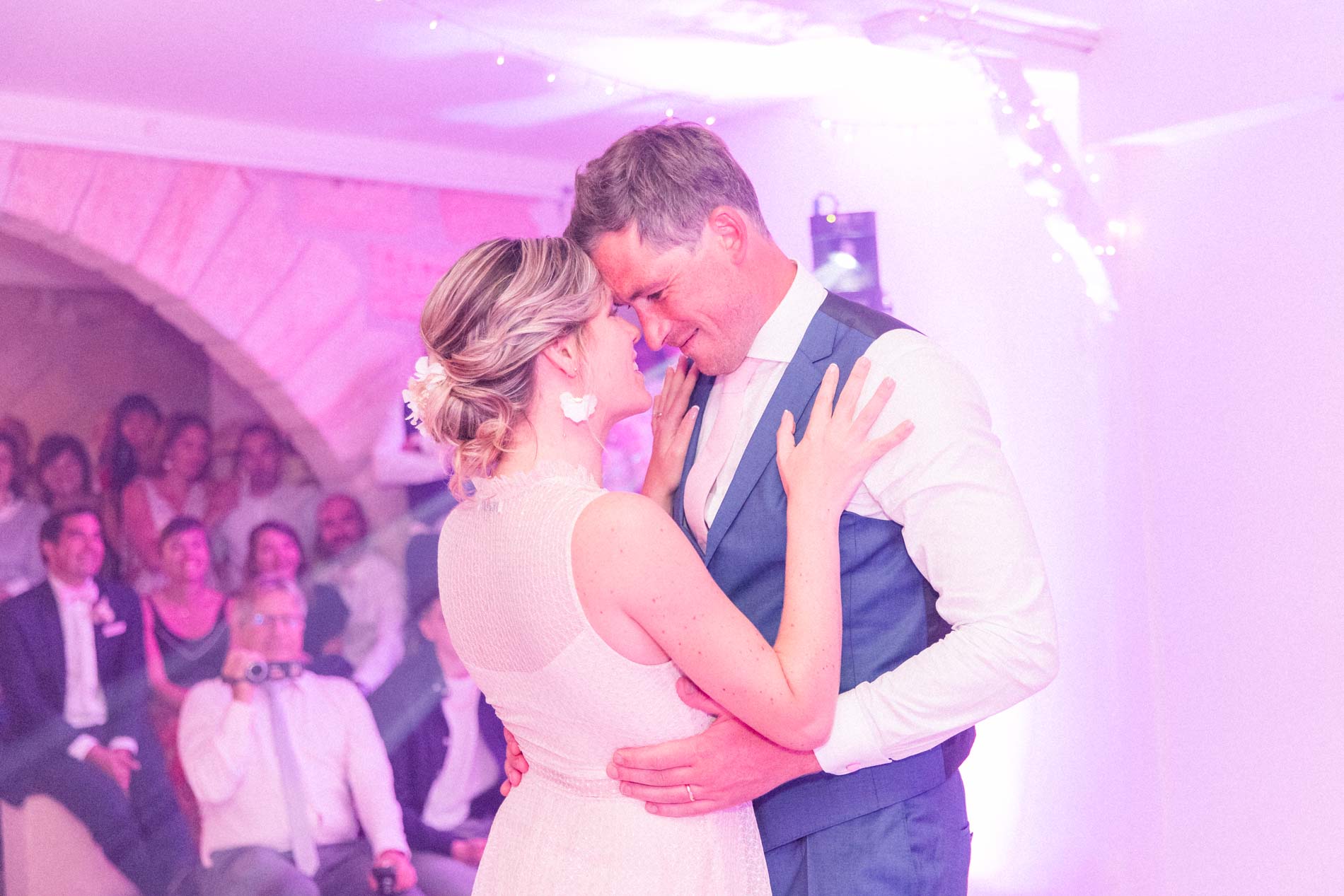 Bride and groom dancing cheek to cheek in front of their guests