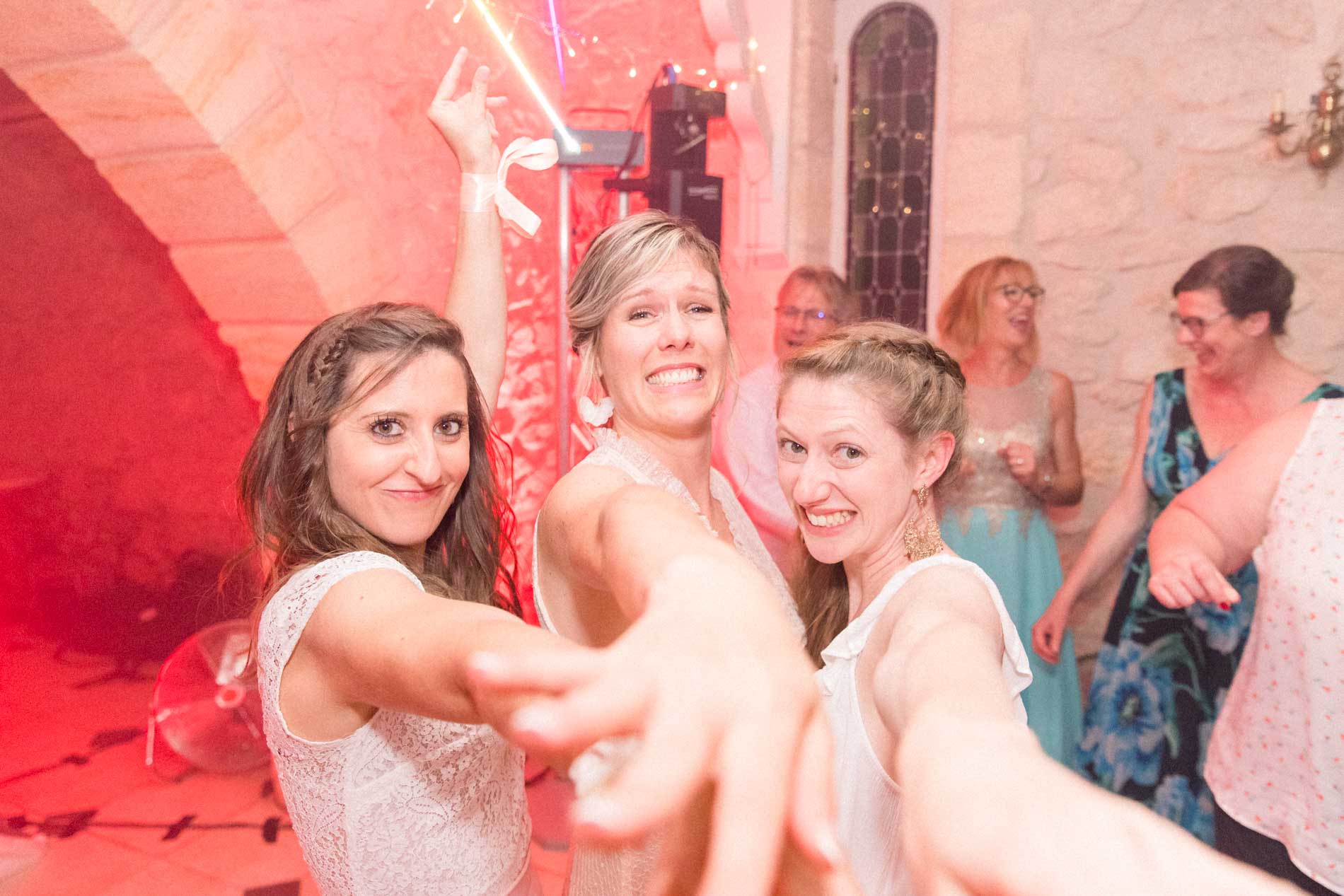 Bride and her friends dancing under red lights at the evening party