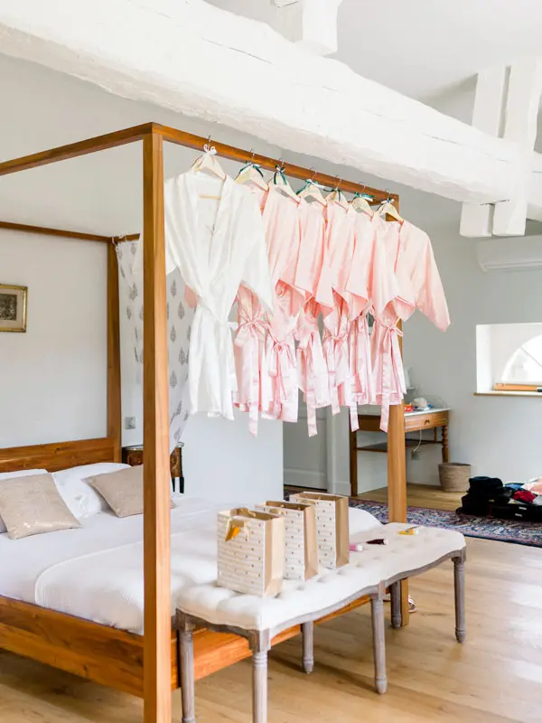 Pink robes hanging from a four-poster bed in the getting-ready suite