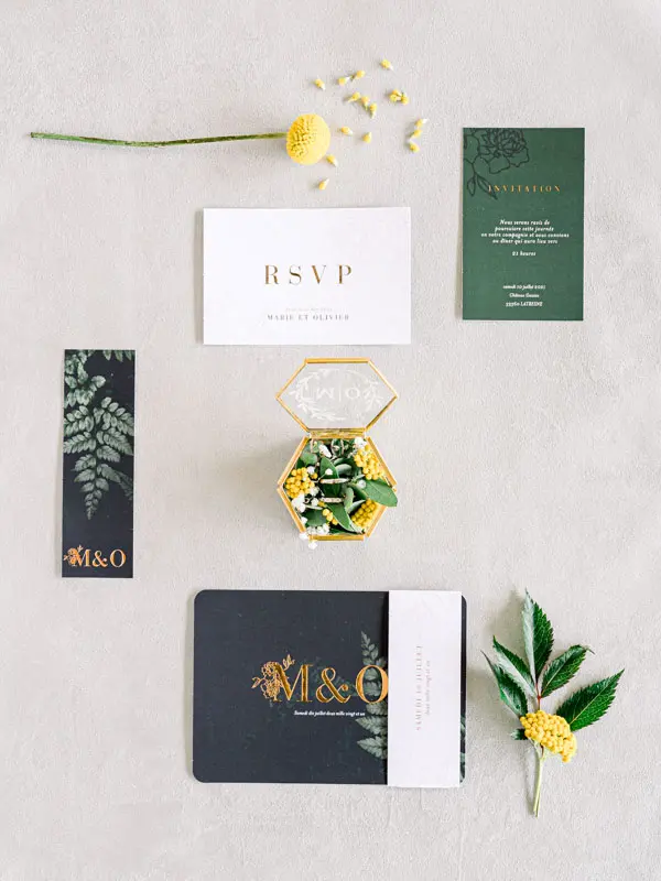 Flat lay of wedding stationery, ring box and yellow flowers