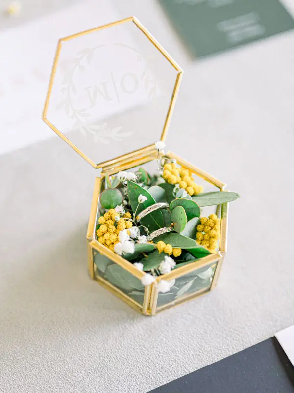 Hexagonal glass and brass ring box filled with yellow flowers