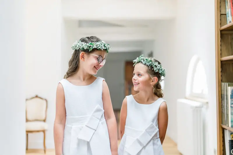 Two little flower girls in white dresses and floral crowns
